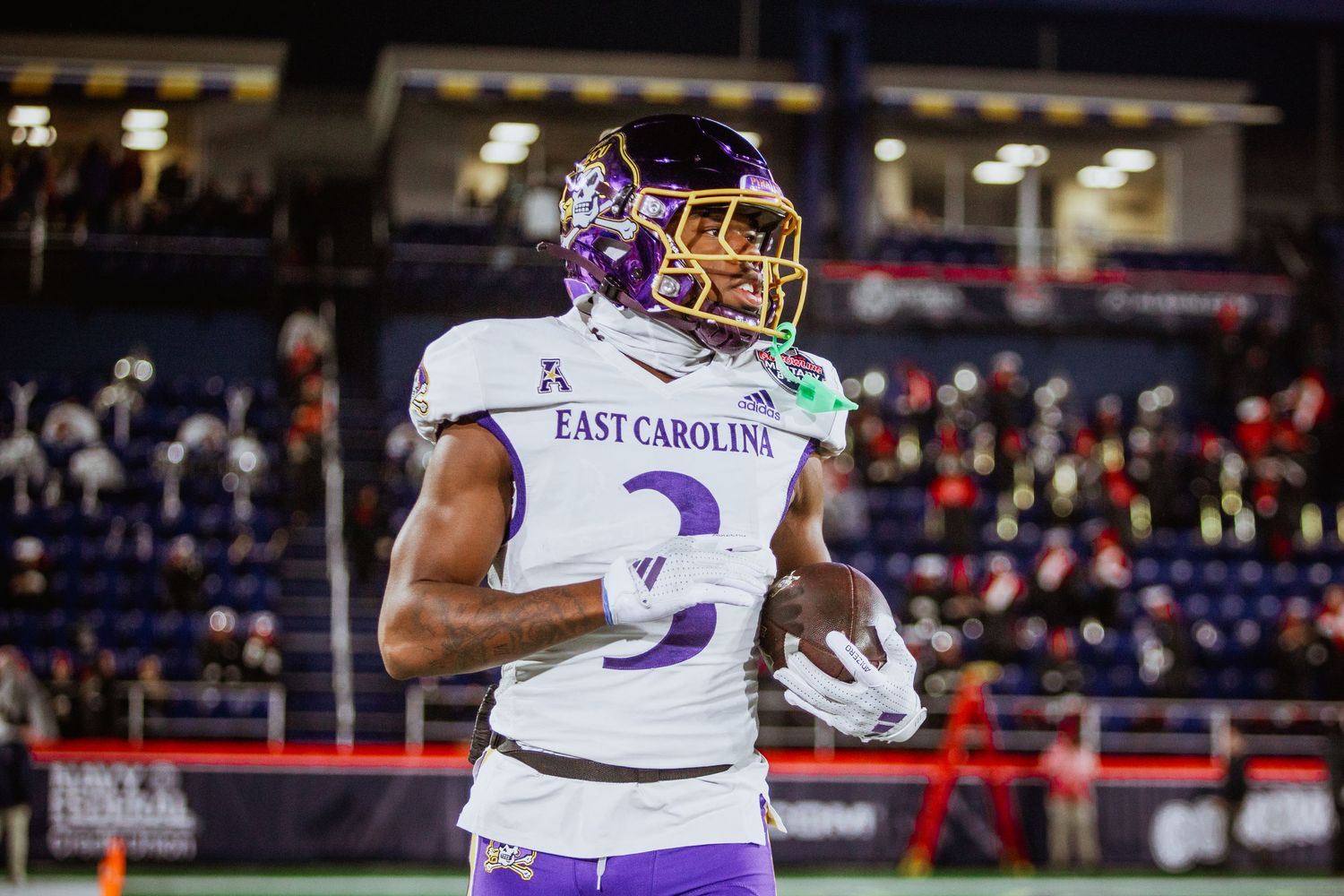 East Carolina Pirates wide receiver number 3 in purple uniform warming up on field during bowl game.