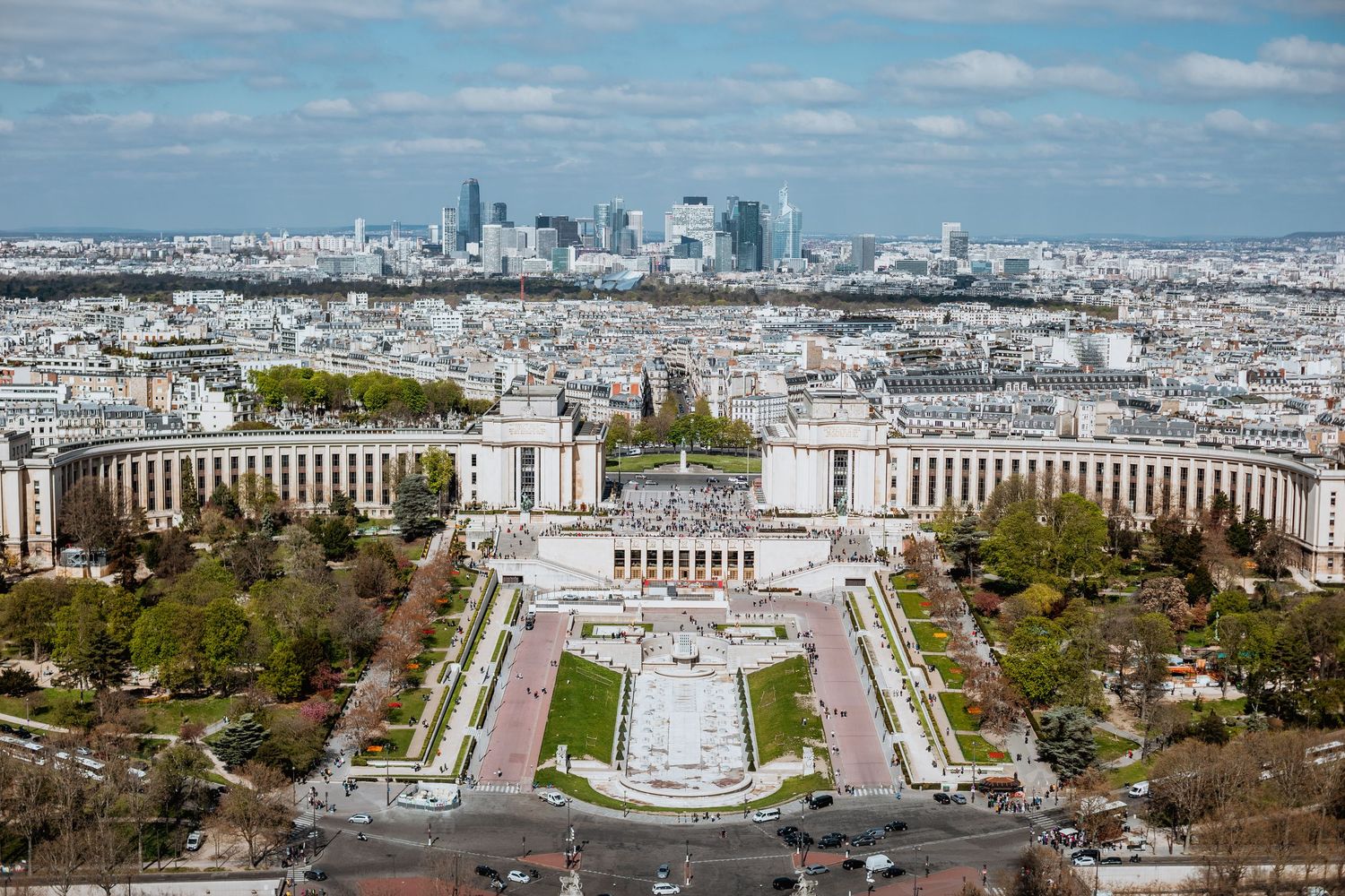 Aerial view of Trocadero gardens and plaza in Paris with La Defense skyline in the distance.