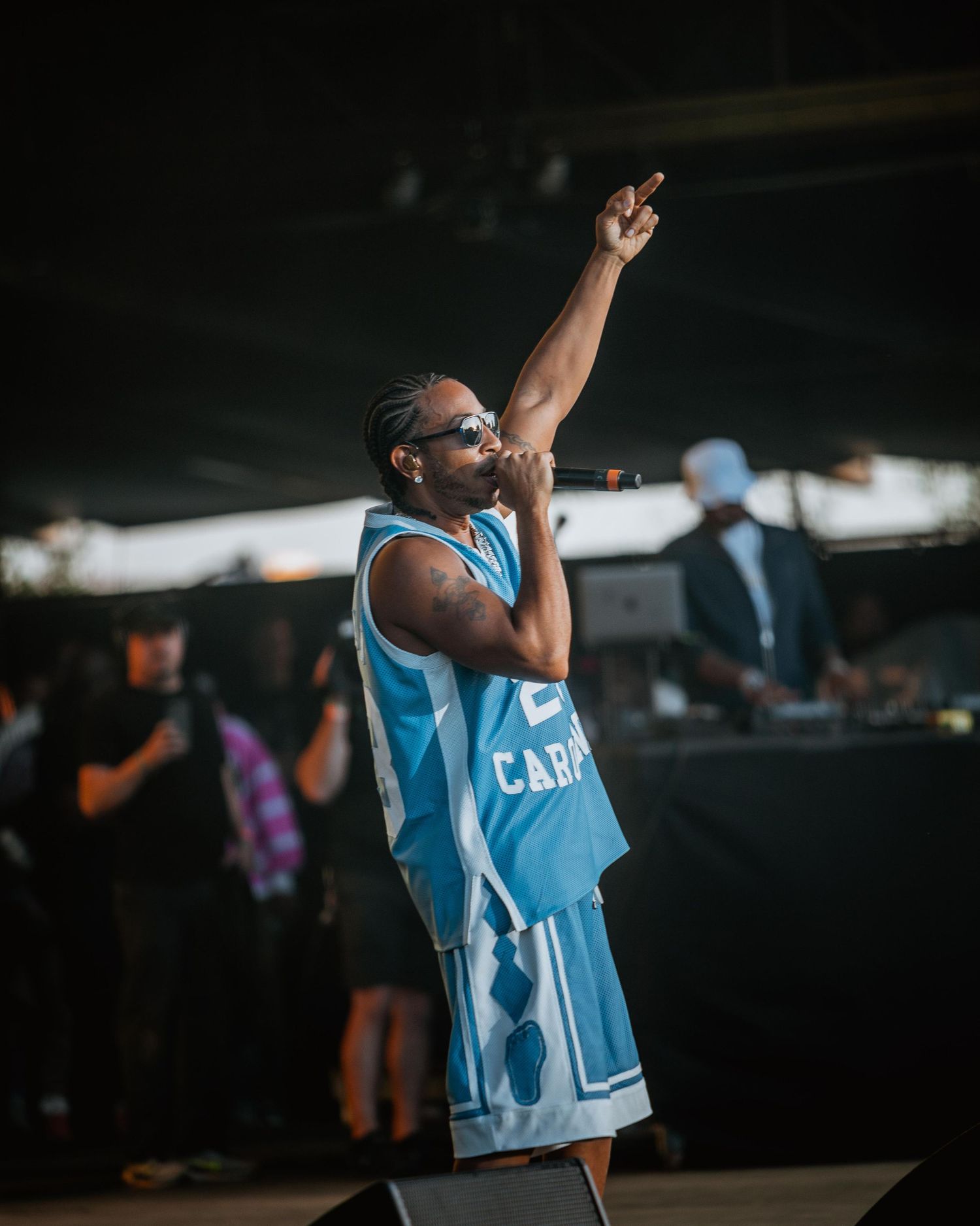 Male artist in Carolina jersey raising hand while performing on stage.