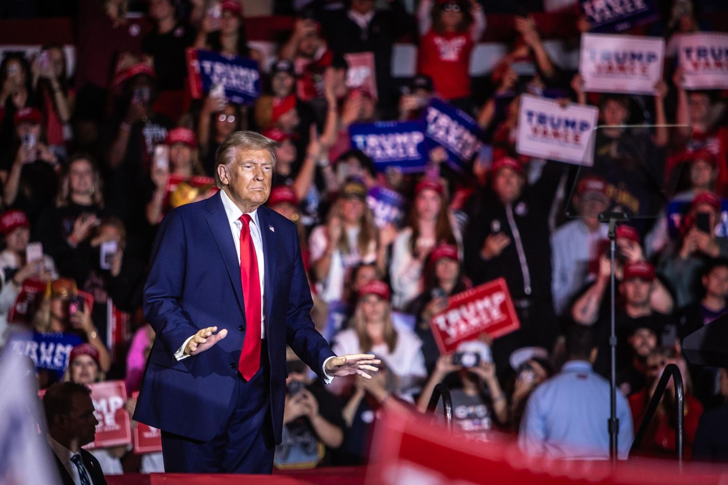 Donald Trump gestures to the crowd at a large campaign rally with supporters waving Trump Vance signs.