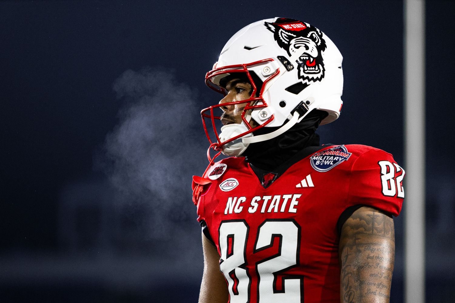 NC State Wolfpack player number 82 in red jersey with visible breath vapor during cold night football game.