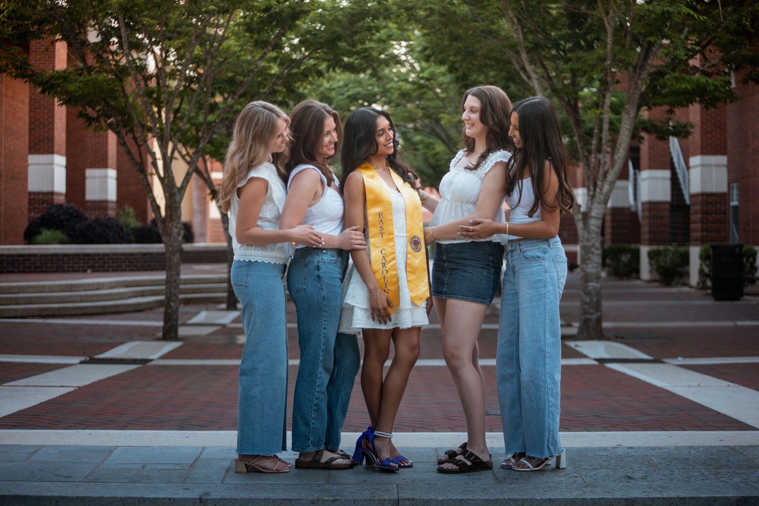 Five young women pose together outdoors on a brick plaza at East Carolina University campus.