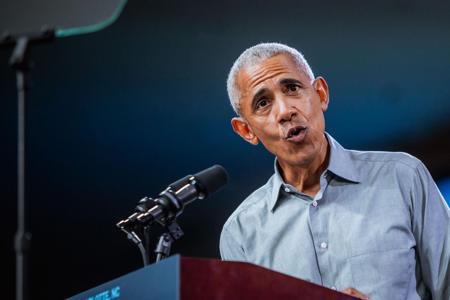 Man with gray hair speaking at a podium with a microphone at a political event.