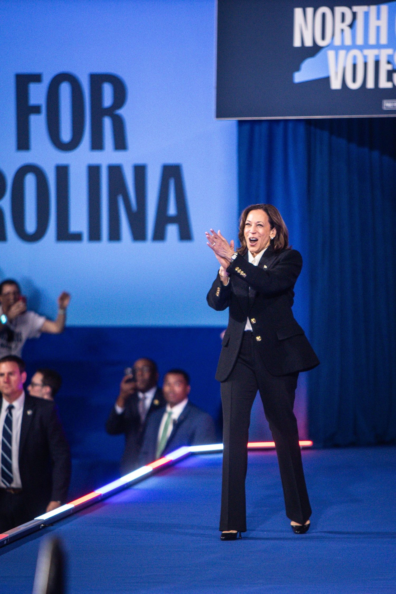 Kamala Harris claps on stage at a North Carolina Votes Early campaign rally.