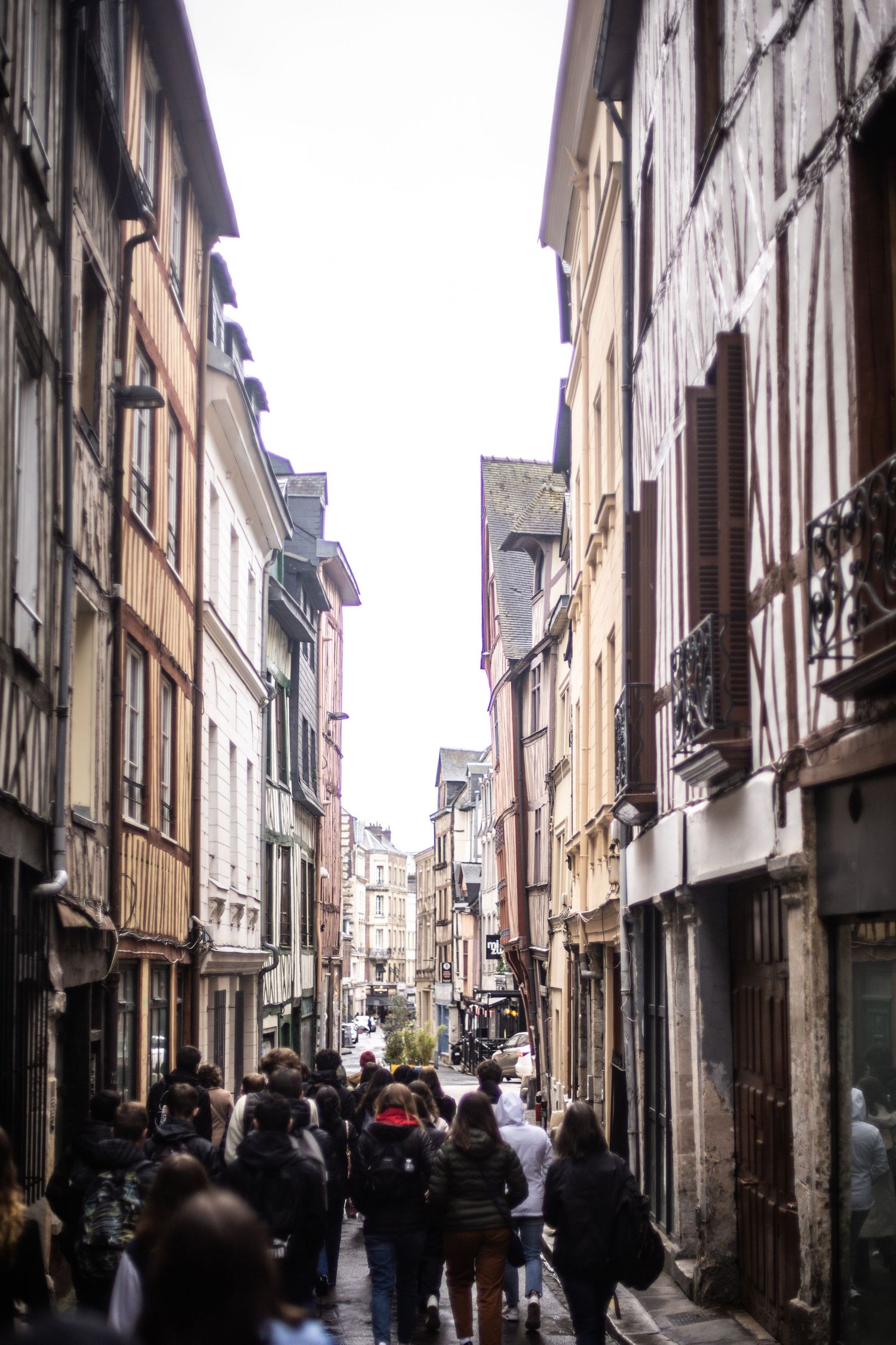 Crowded narrow medieval street lined with half-timbered buildings in old town Rouen, France.