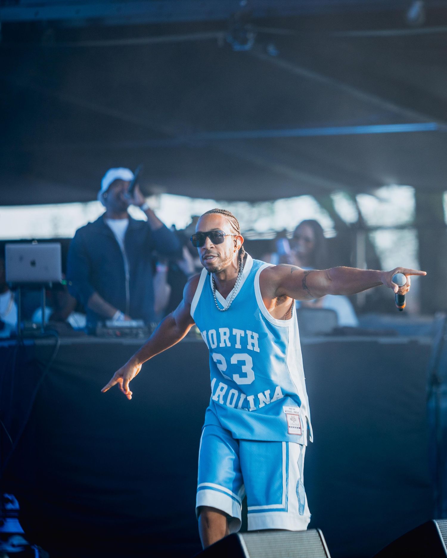 Performer in a North Carolina number 23 basketball jersey and shorts with sunglasses on an outdoor stage.