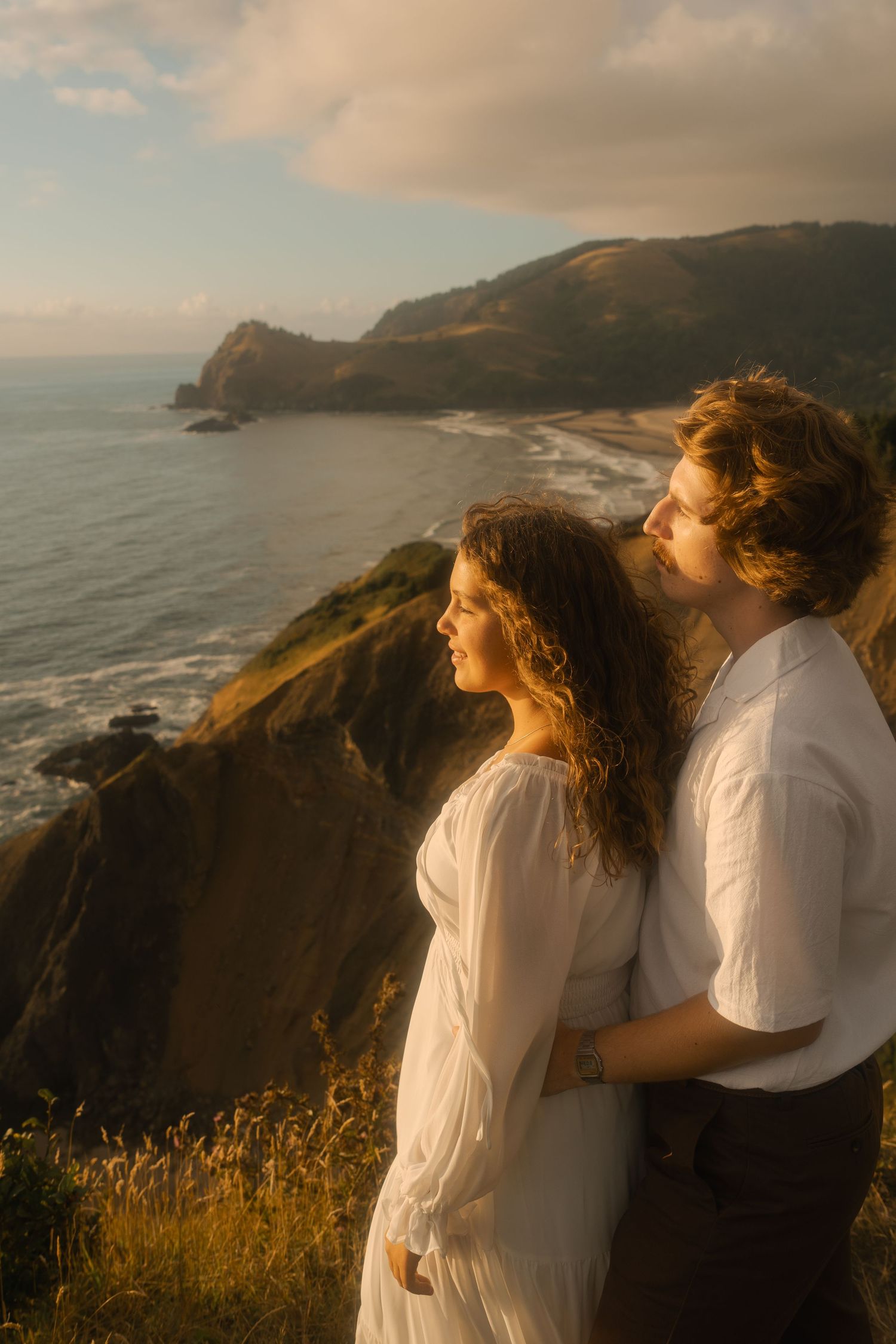 Couple embracing on the cliffs overlooking the Pacific Ocean.