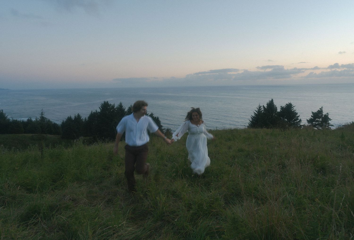 Couple walking hand in hand along God's Thumb trail during an Oregon Coast adventure session at sunset.