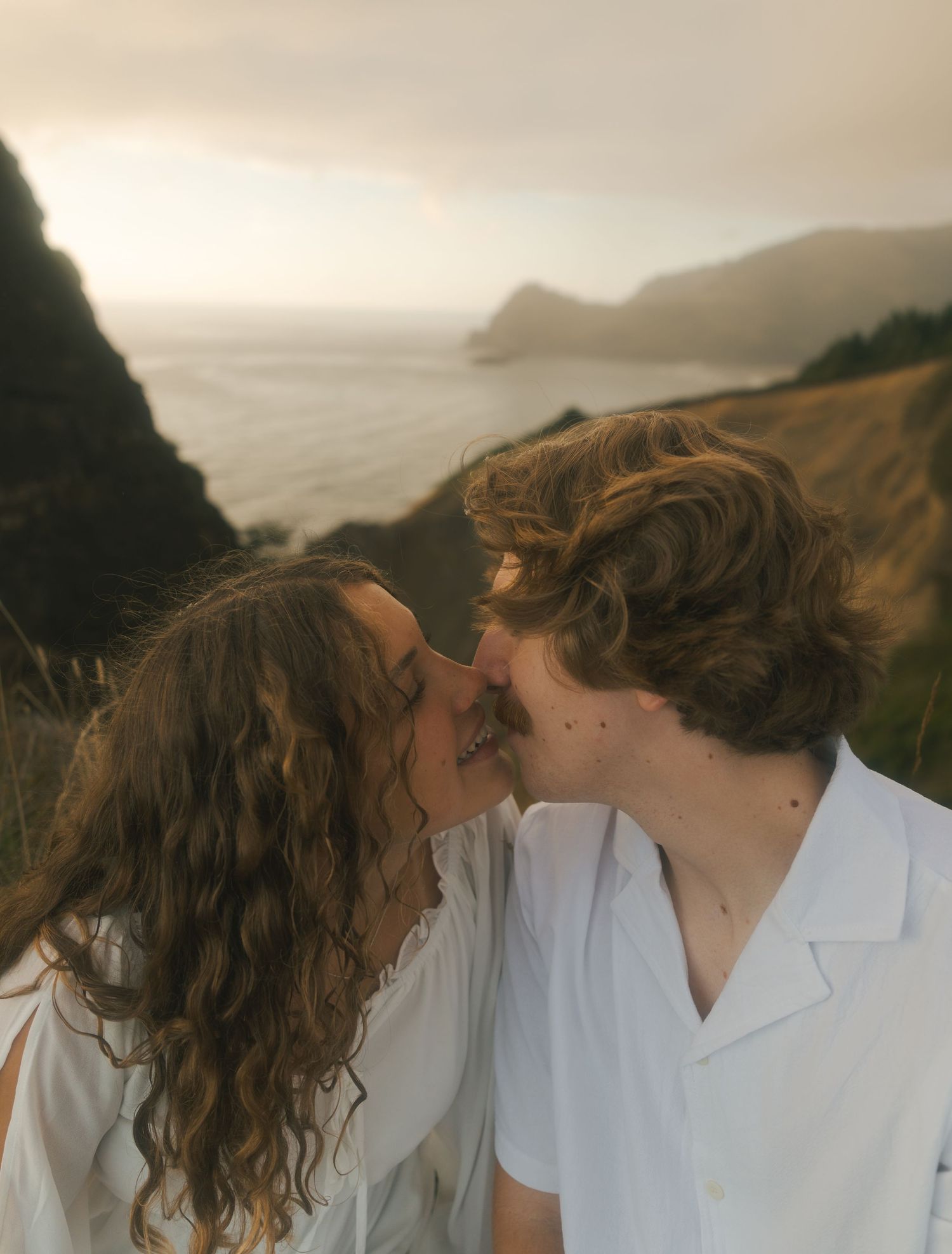 Couple embracing on the cliffs overlooking the Pacific Ocean.