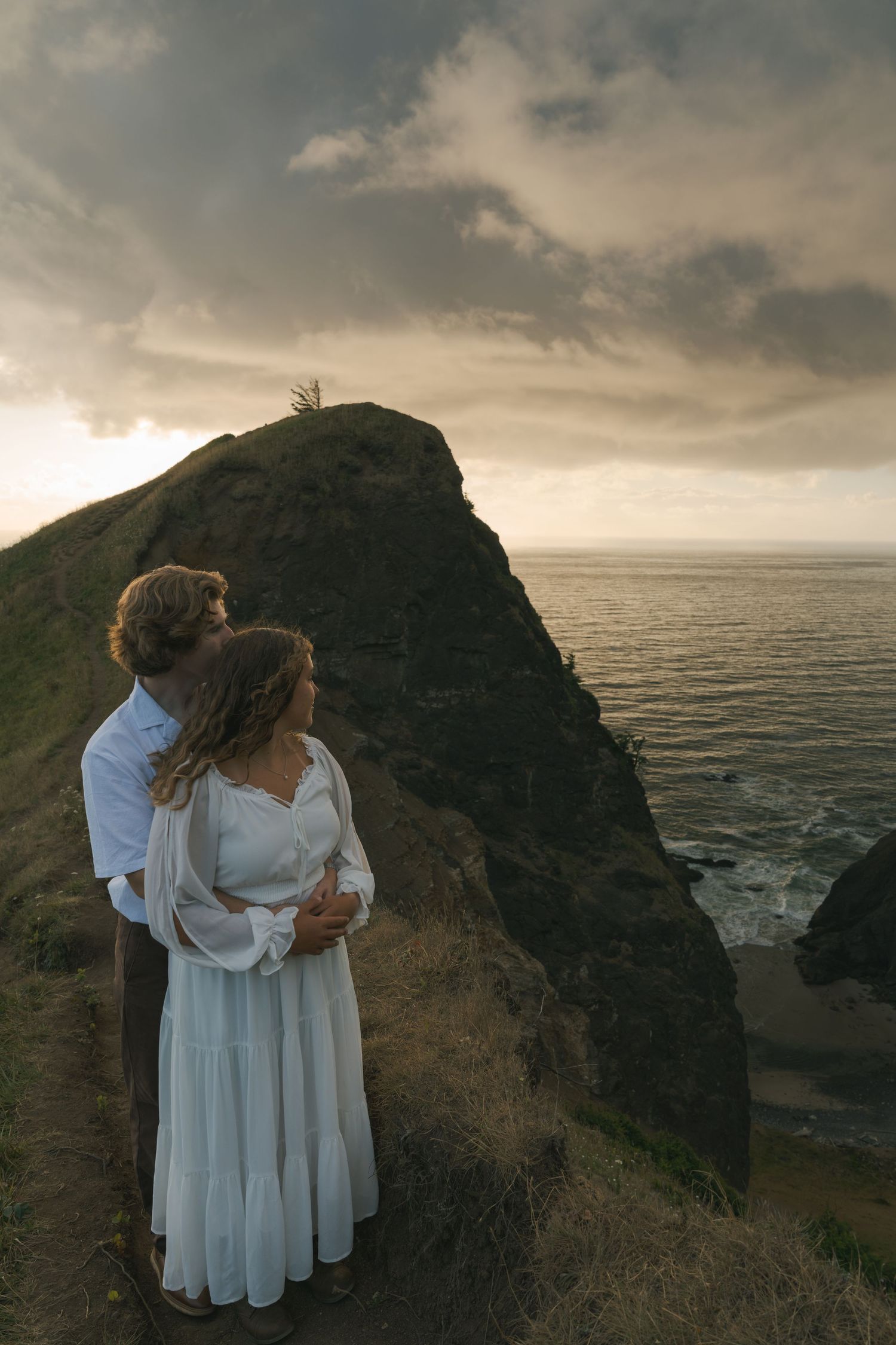 Couple embracing on the cliffs overlooking the Pacific Ocean.