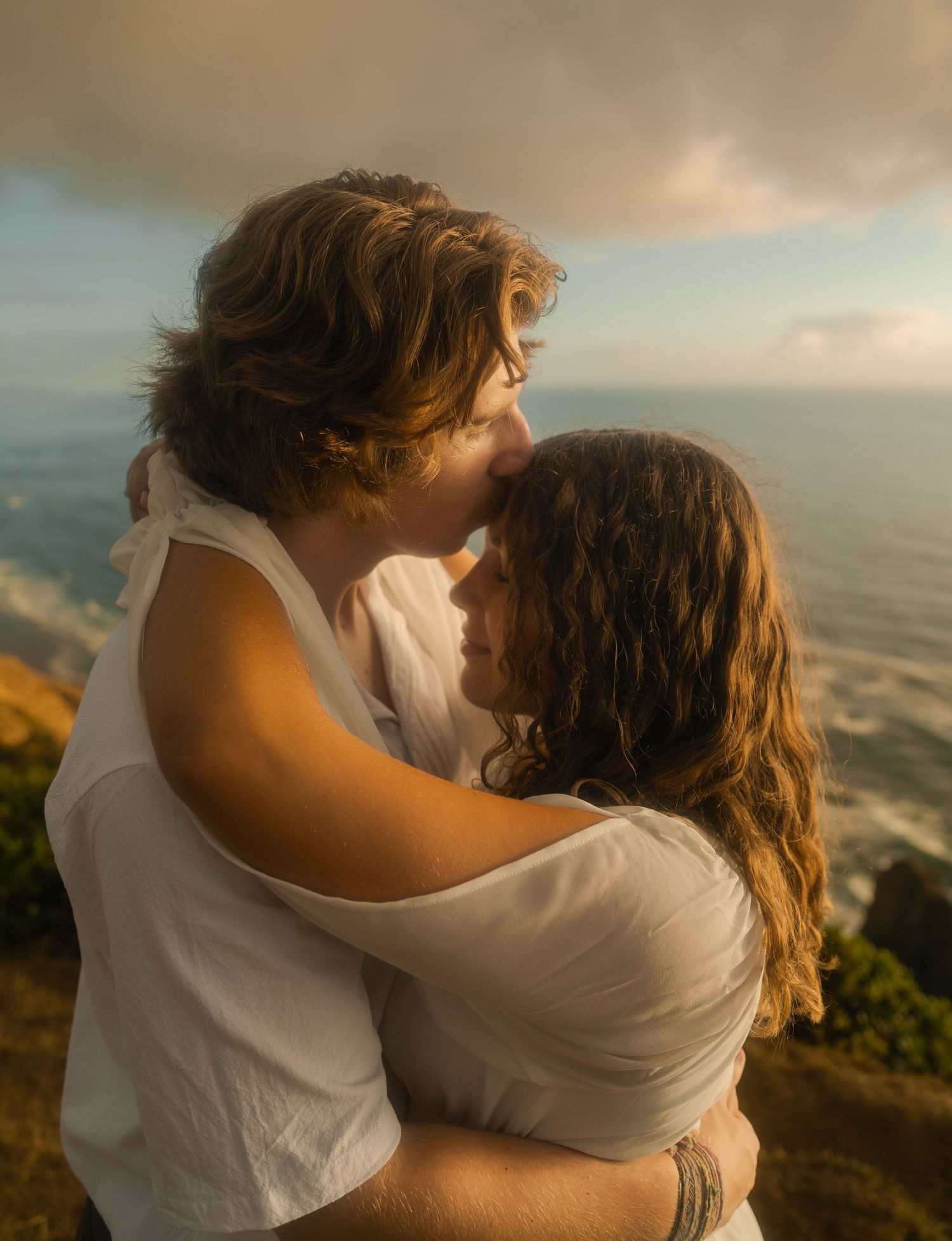 Couple embracing on the cliffs overlooking the Pacific Ocean.