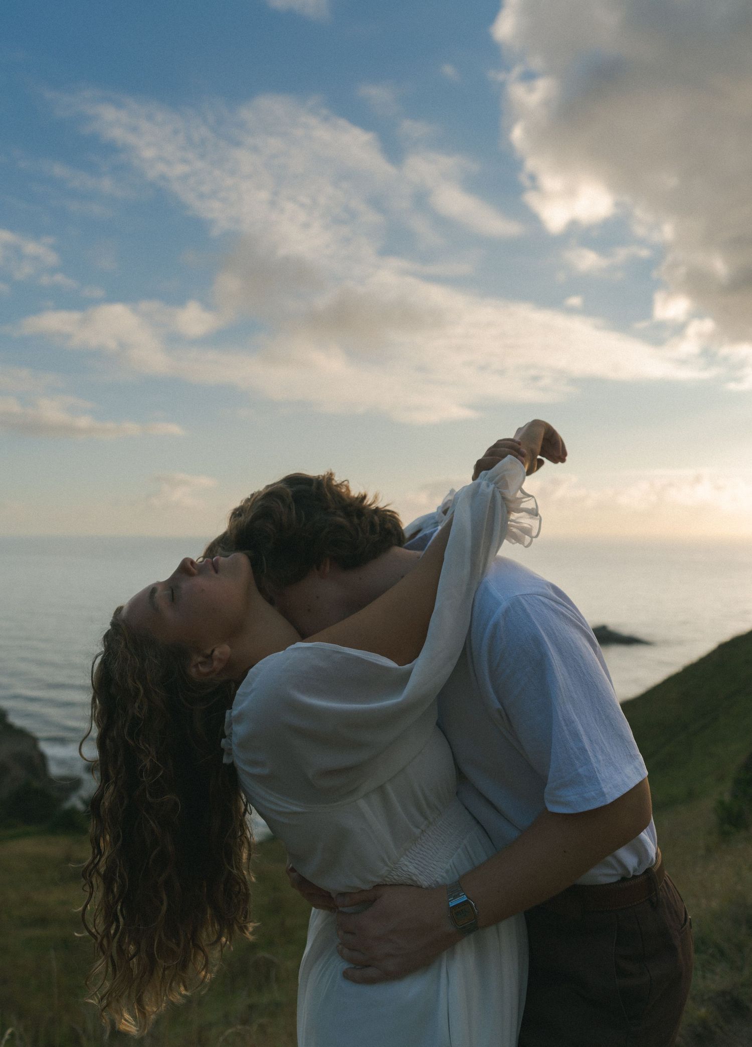 Couple embracing on the cliffs overlooking the Pacific Ocean.
