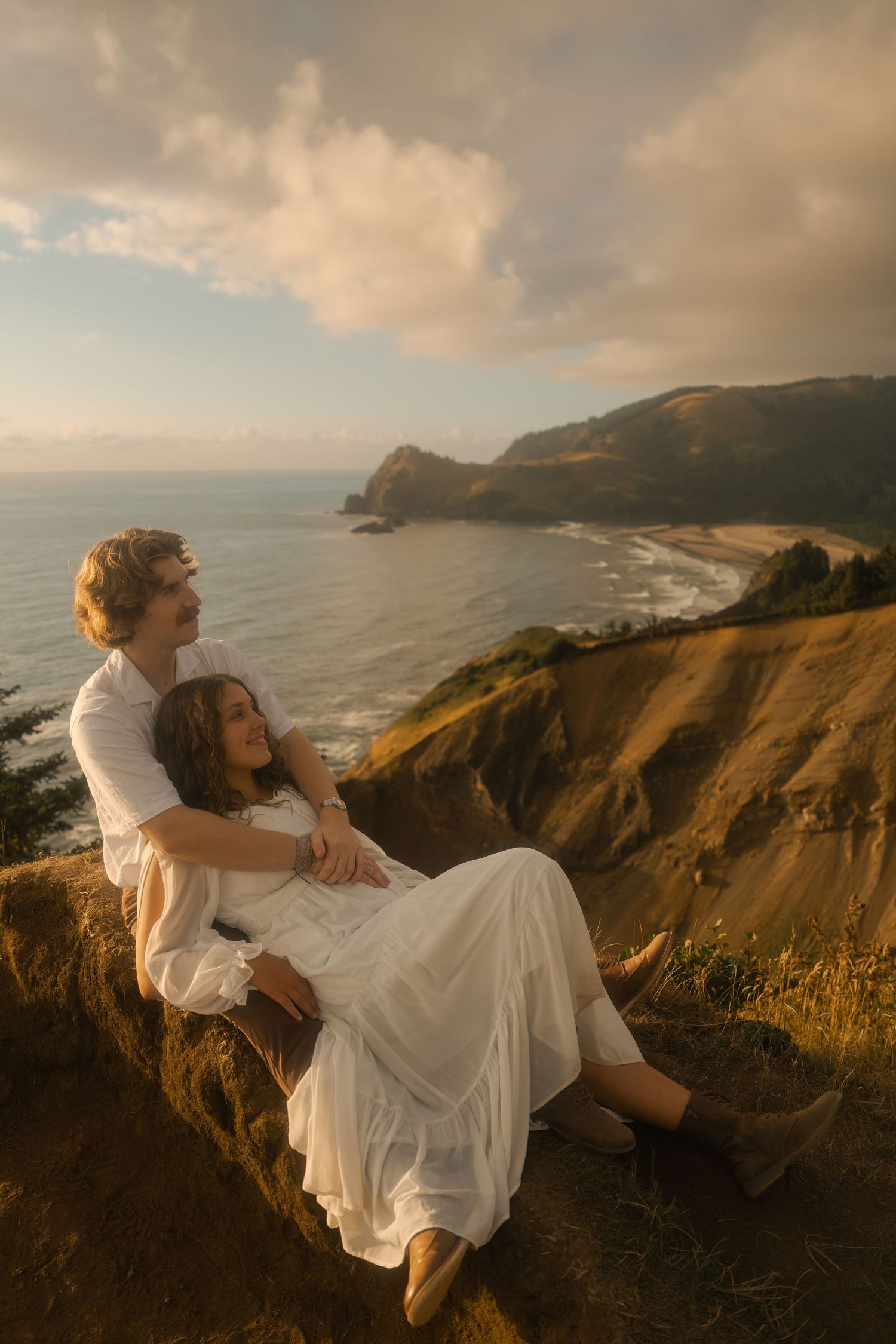 Couple embracing on the cliffs overlooking the Pacific Ocean.