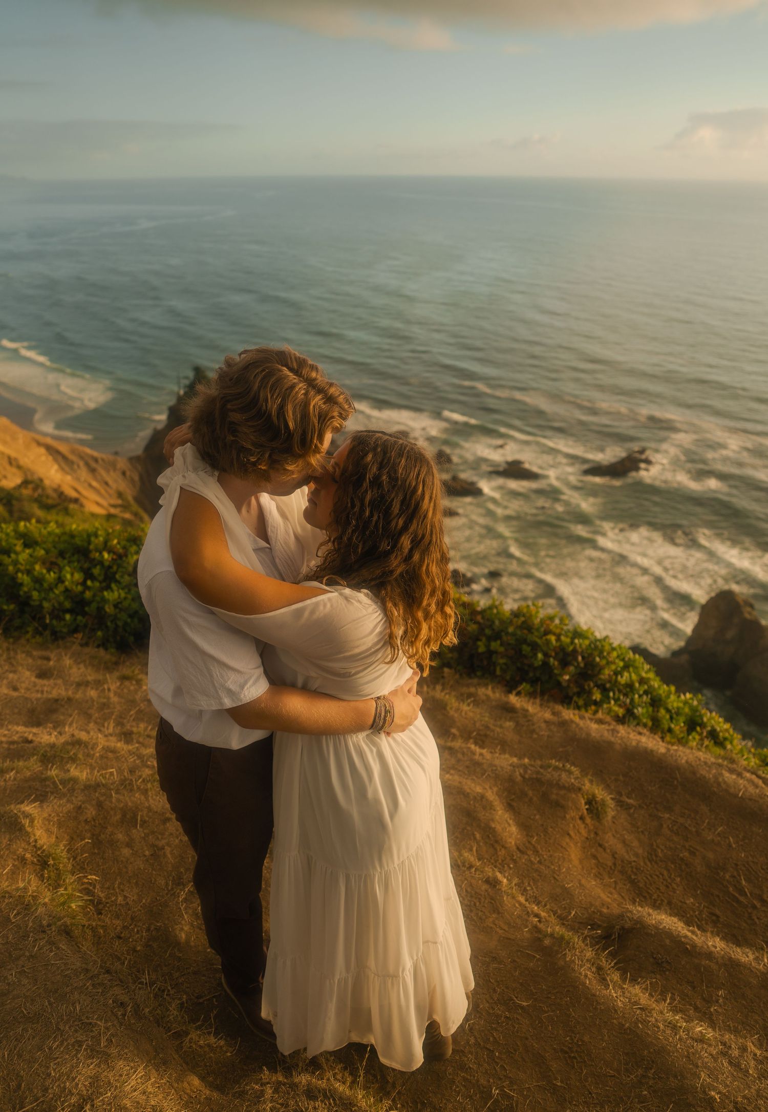 Couple embracing on the cliffs overlooking the Pacific Ocean.