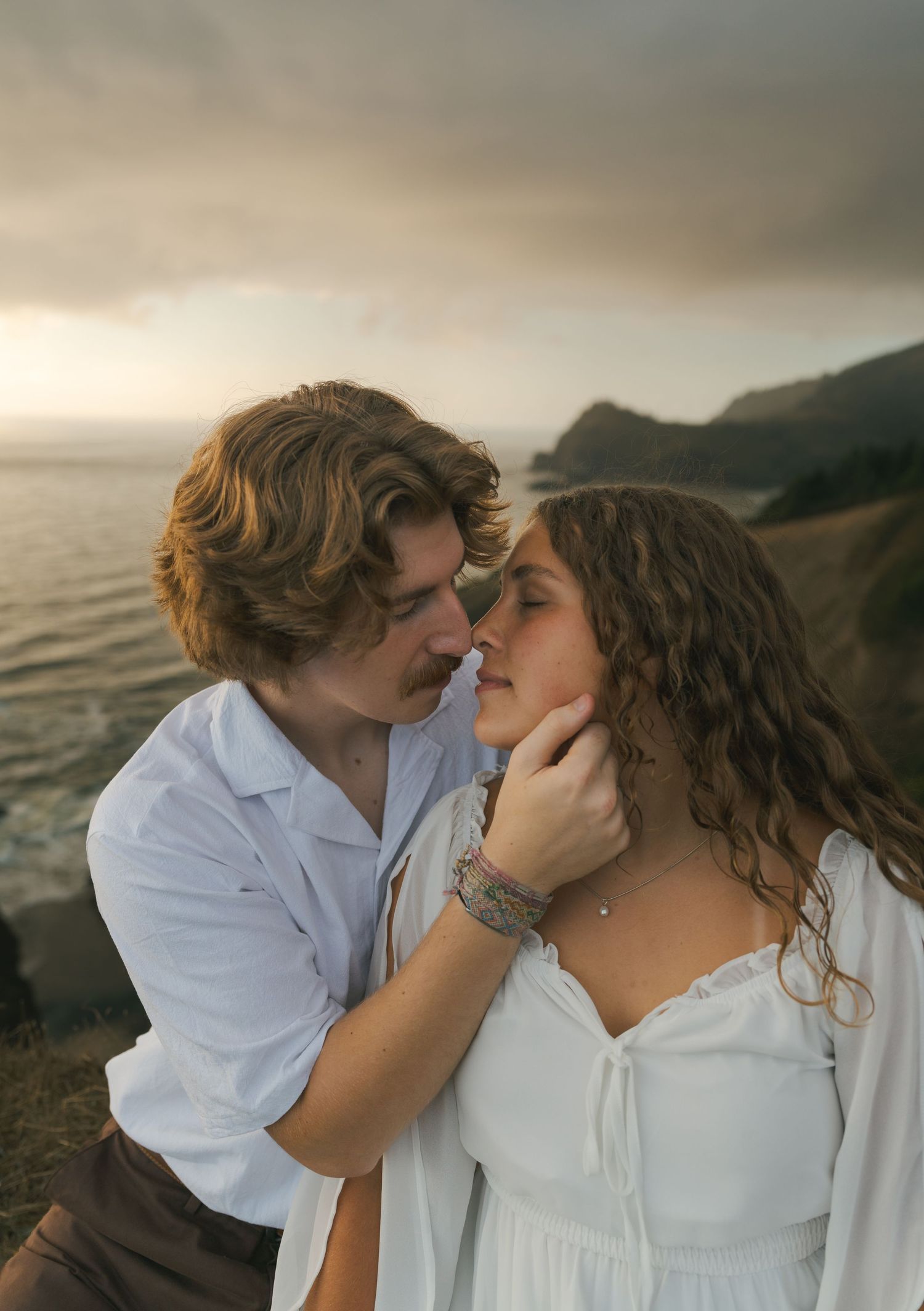 Couple embracing on the cliffs overlooking the Pacific Ocean.