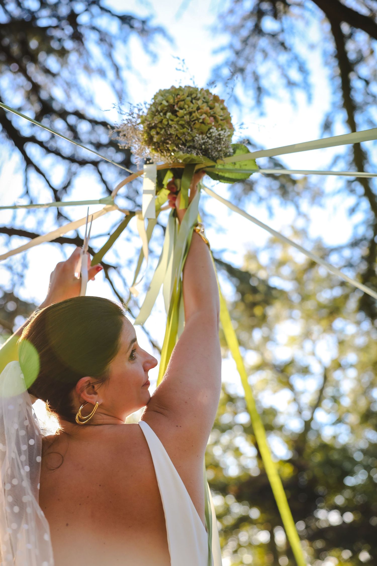 Animation de mariage originale : la mariée coupe les rubans du bouquet entourée de ses amies. Moment de partage lumineux et authentique.