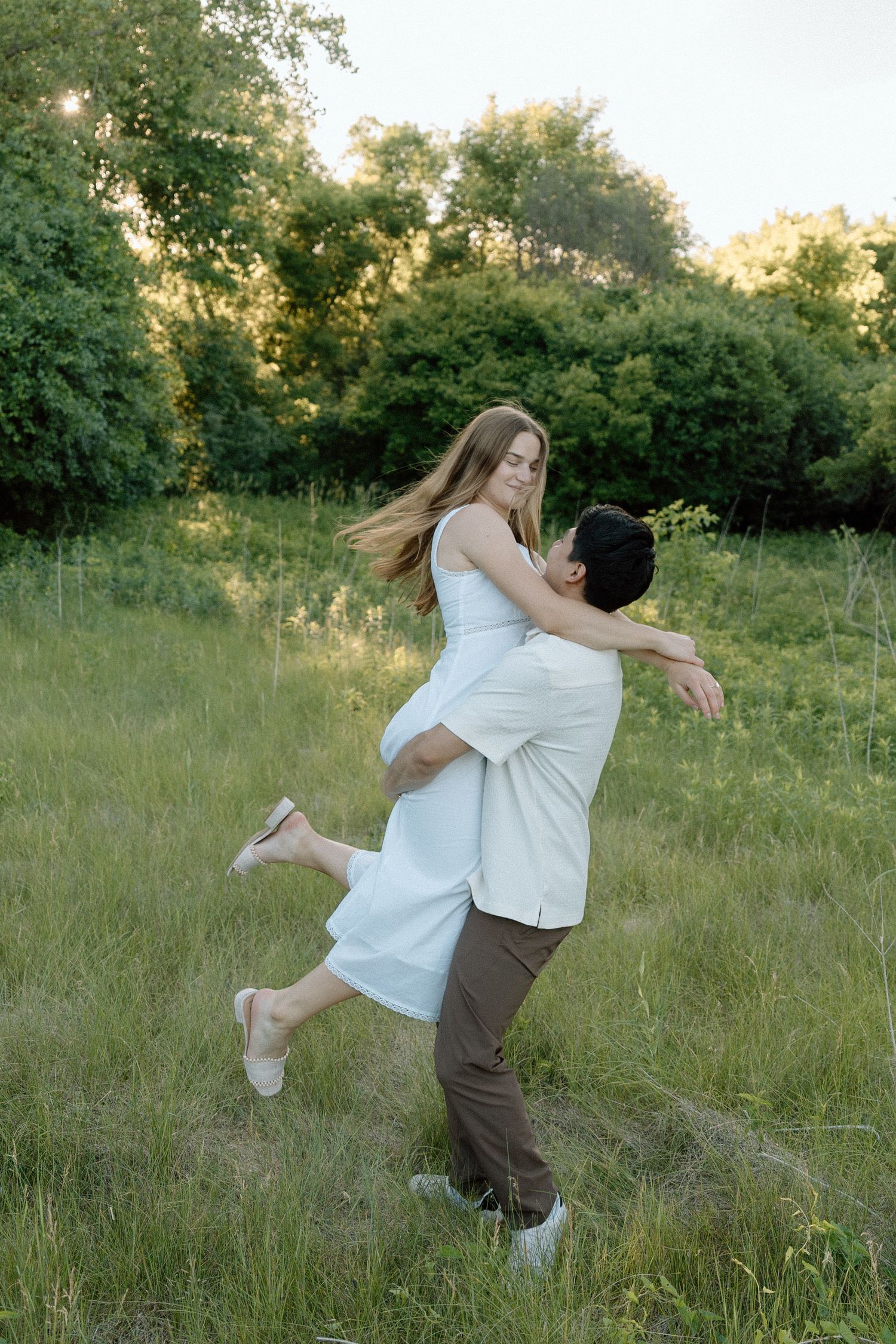 Spin her around in an engagement shoot in a field on a summer evening