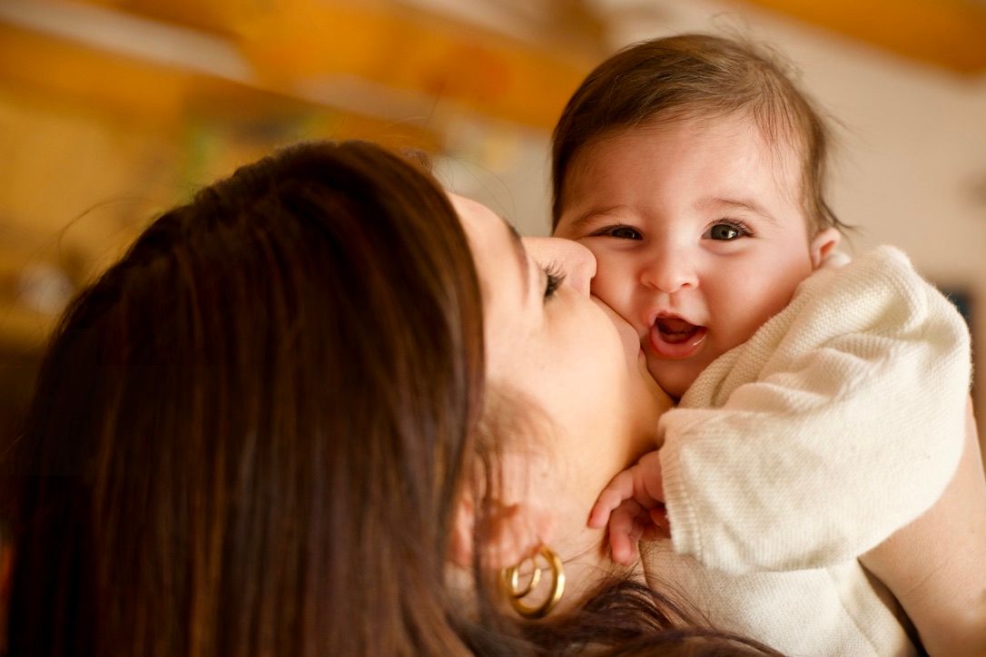 Maman embrassant son bébé dans une ambiance chaleureuse, moment de vie tendre et authentique.