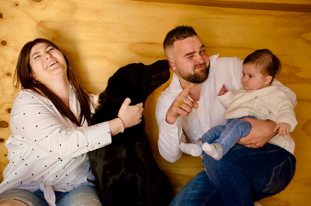 Famille allongée avec leur chien et leur bébé, instant de vie spontané et convivial.