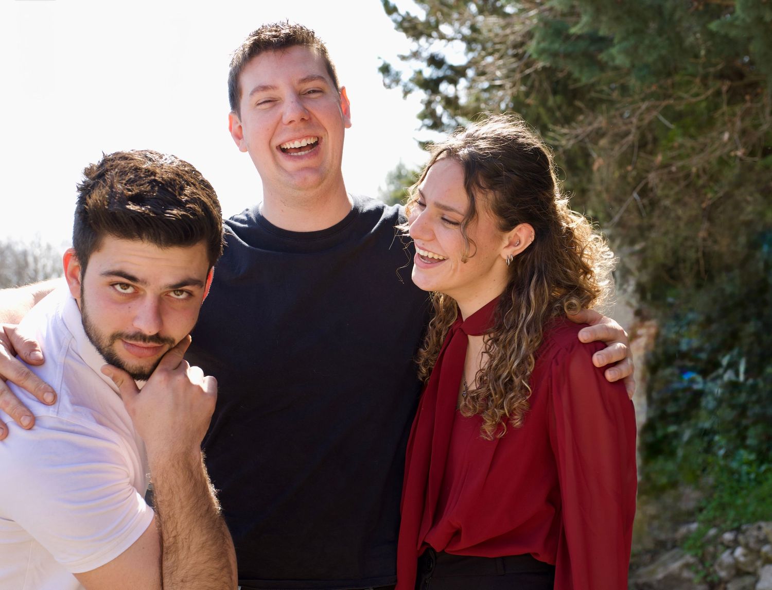 Trois amis souriants en extérieur, moment convivial et authentique capturé en lumière naturelle.