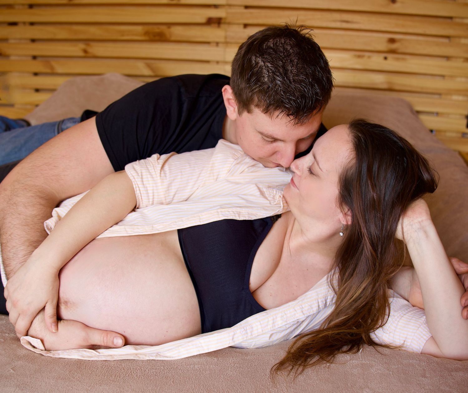 Couple attendant un bébé lors d’une séance grossesse naturelle, moment tendre et complice en intérieur.