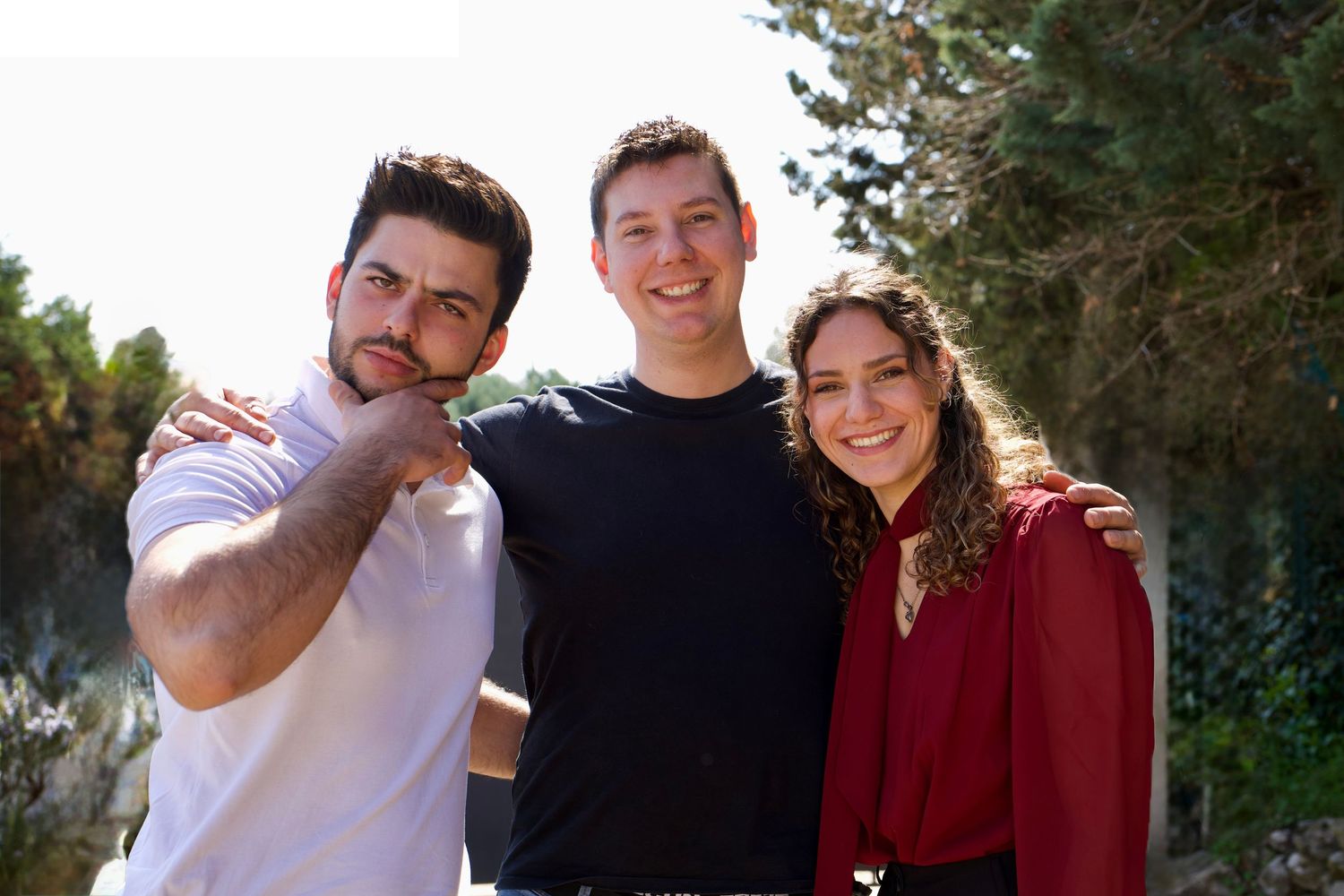 Trois amis posant ensemble au soleil, ambiance conviviale et authentique en extérieur.