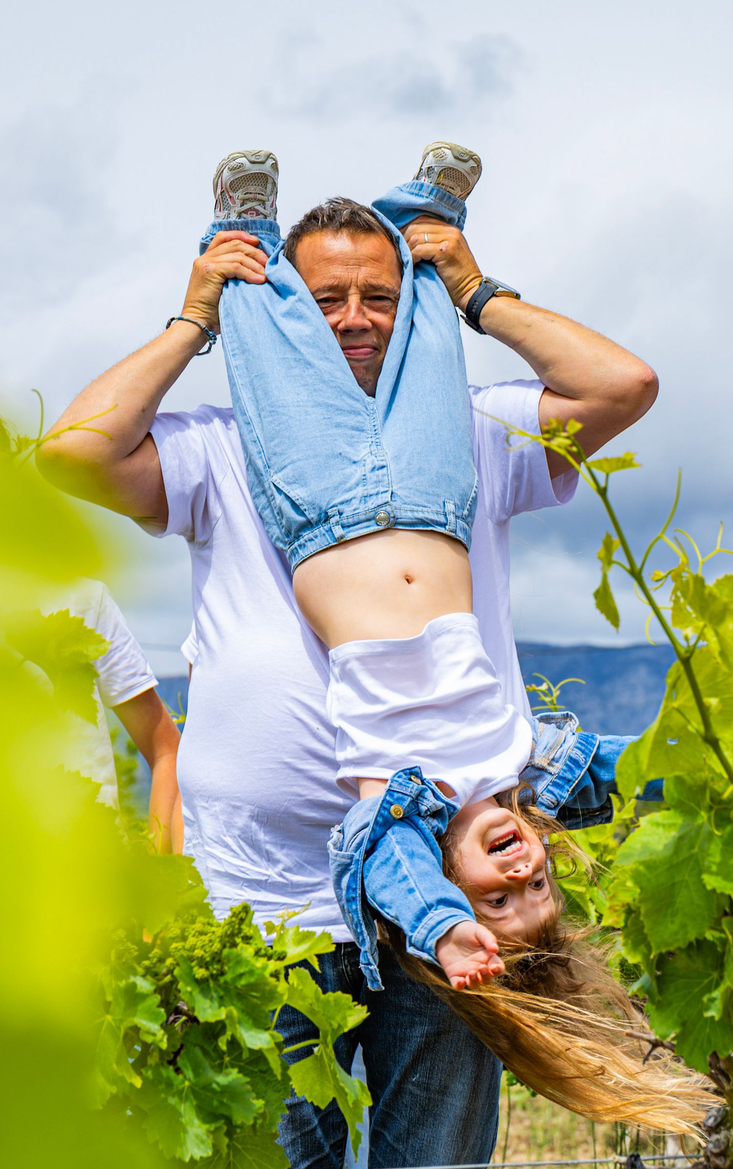 Père portant sa fille sur ses épaules dans les vignes, moment de famille joyeux et naturel en Provence.