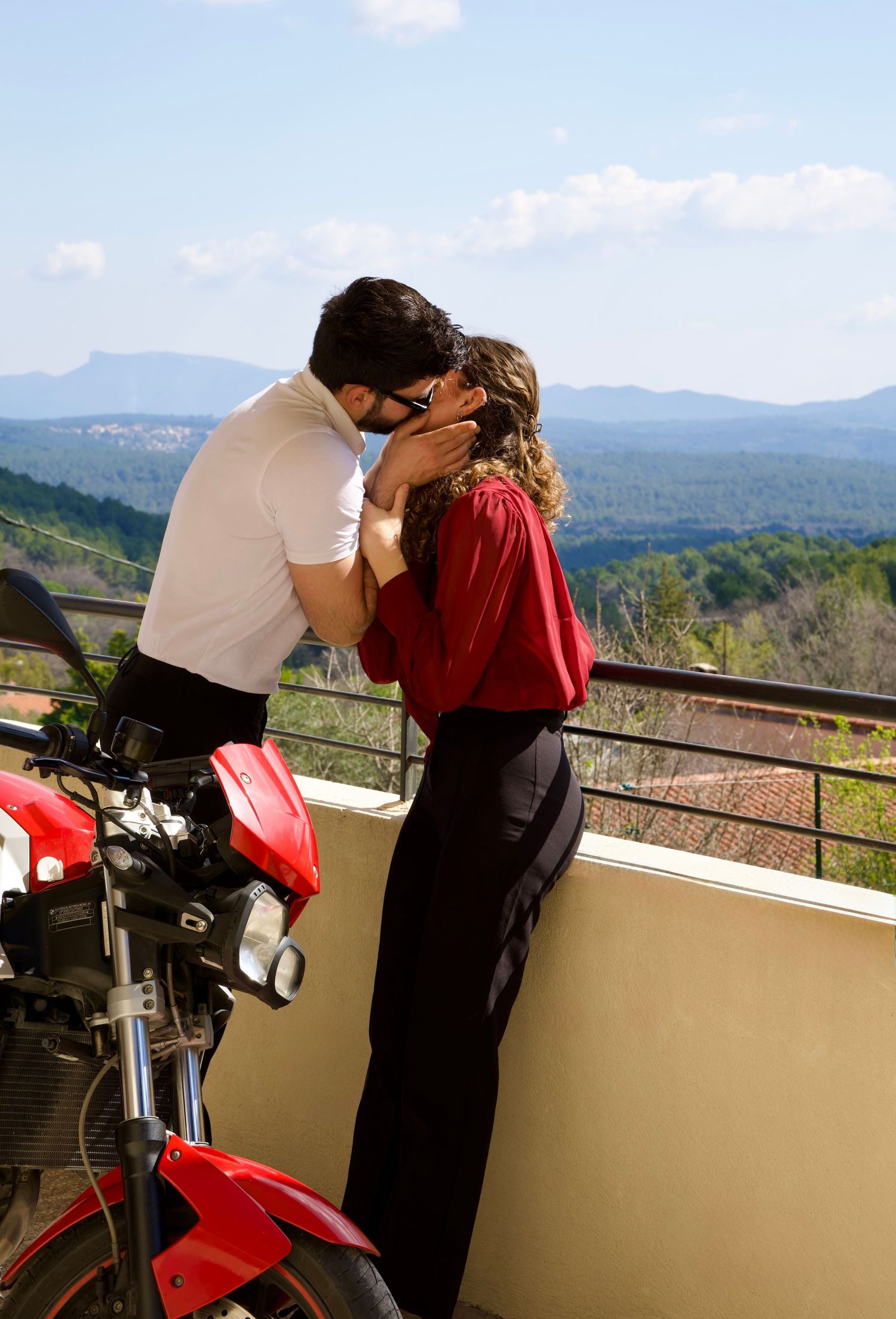 Couple enlacé sur une terrasse avec vue dégagée, instant tendre capturé en lumière naturelle.