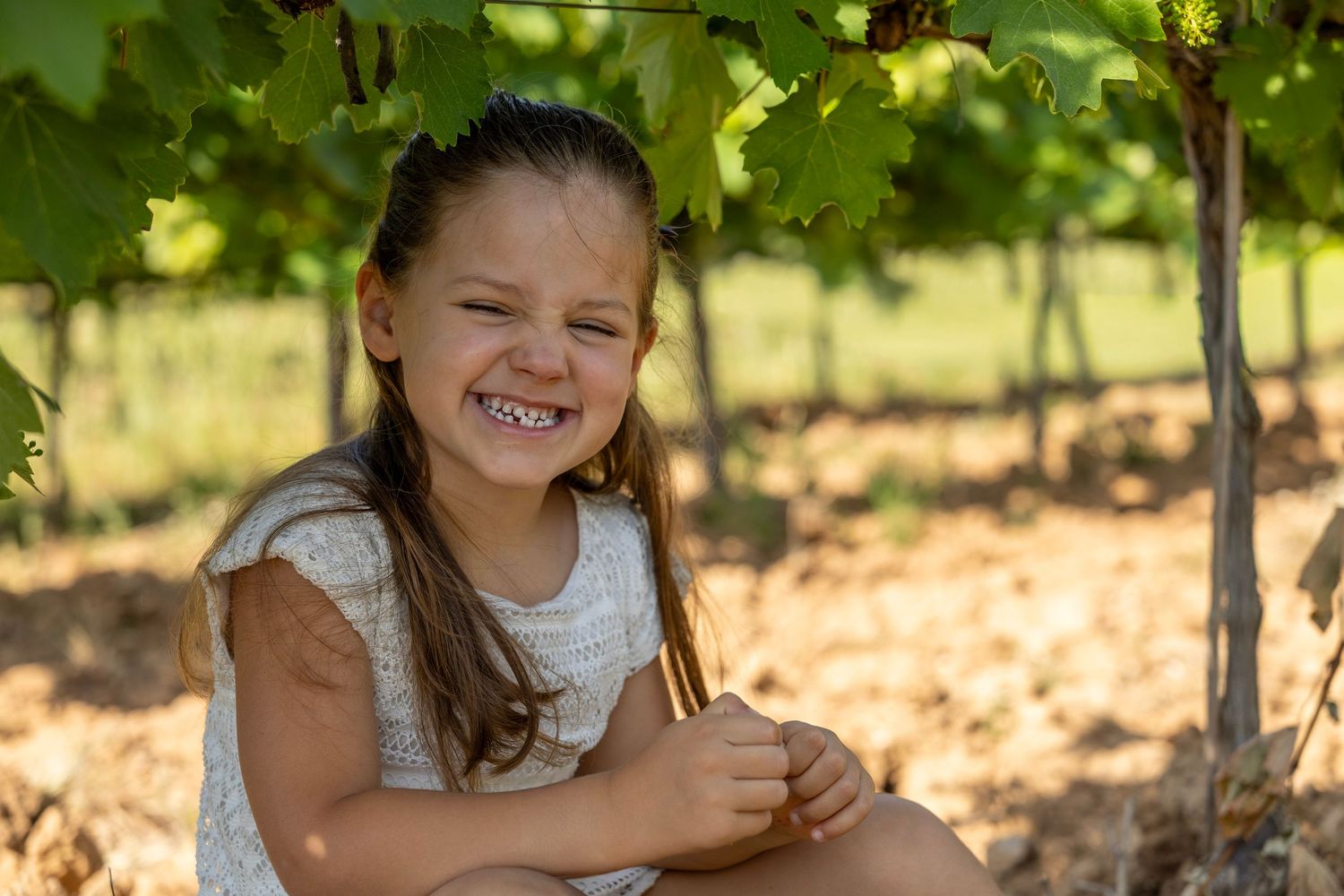 Enfant assise sous les vignes pendant une séance photo famille naturelle dans le Var