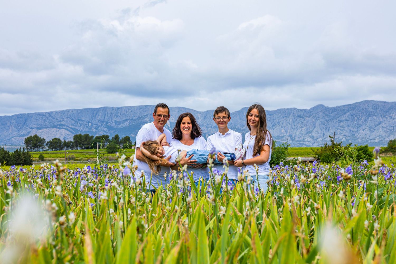 Maman portant son enfant dans un champ fleuri, moment tendre et authentique en Provence.