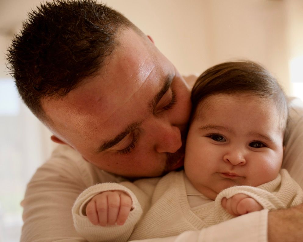 Papa embrassant son bébé avec affection, instant de vie tendre capturé en lumière naturelle.