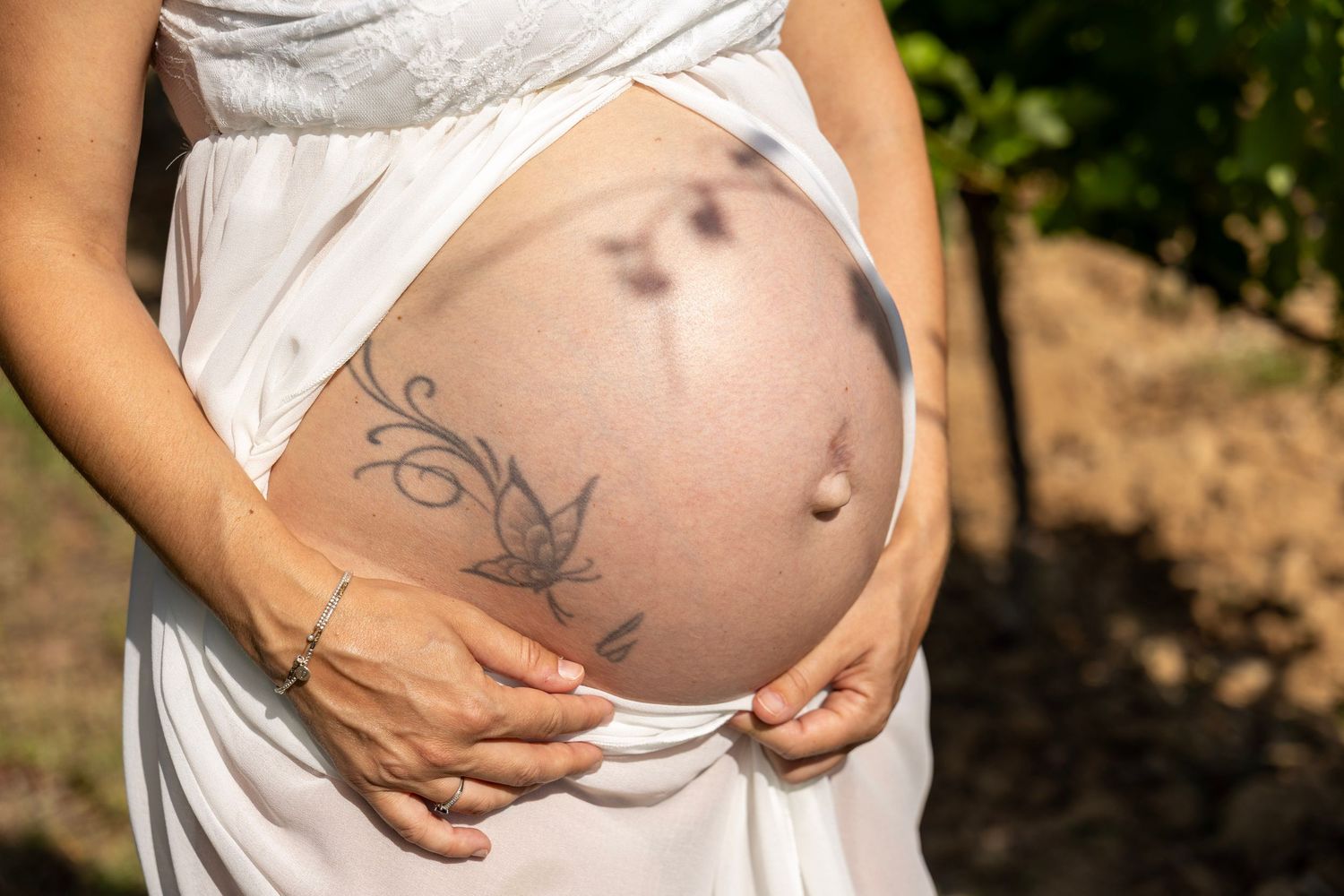 Future maman tenant son ventre pendant une séance photo maternité naturelle en Provence