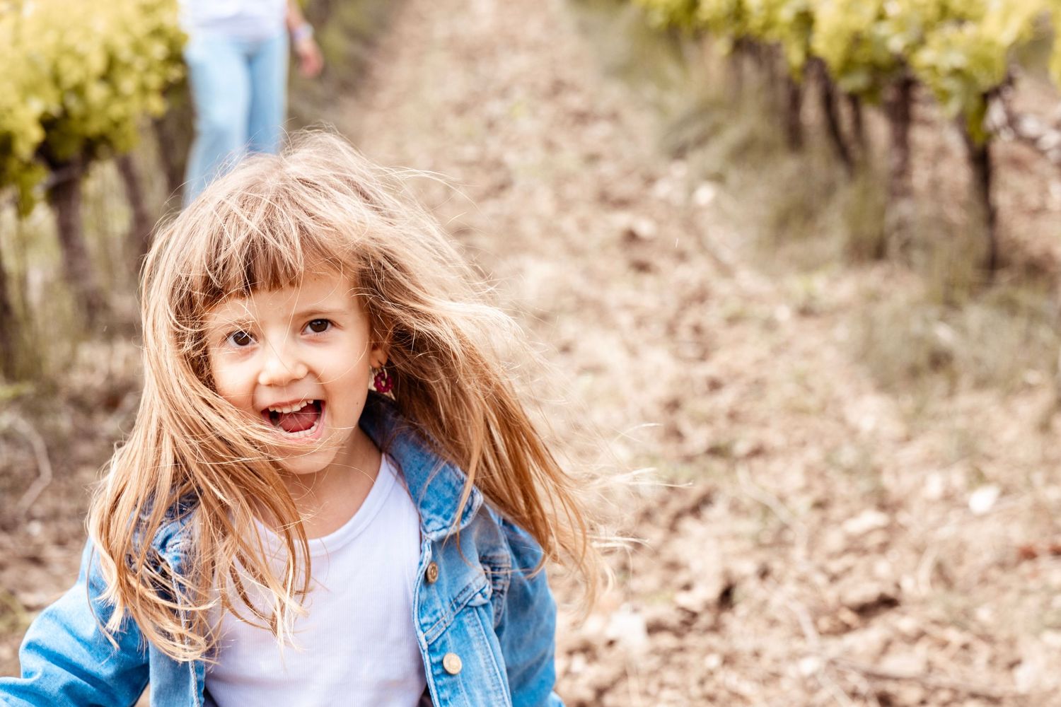 Petite fille souriante dans les vignes en Provence, portrait spontané et naturel en extérieur.