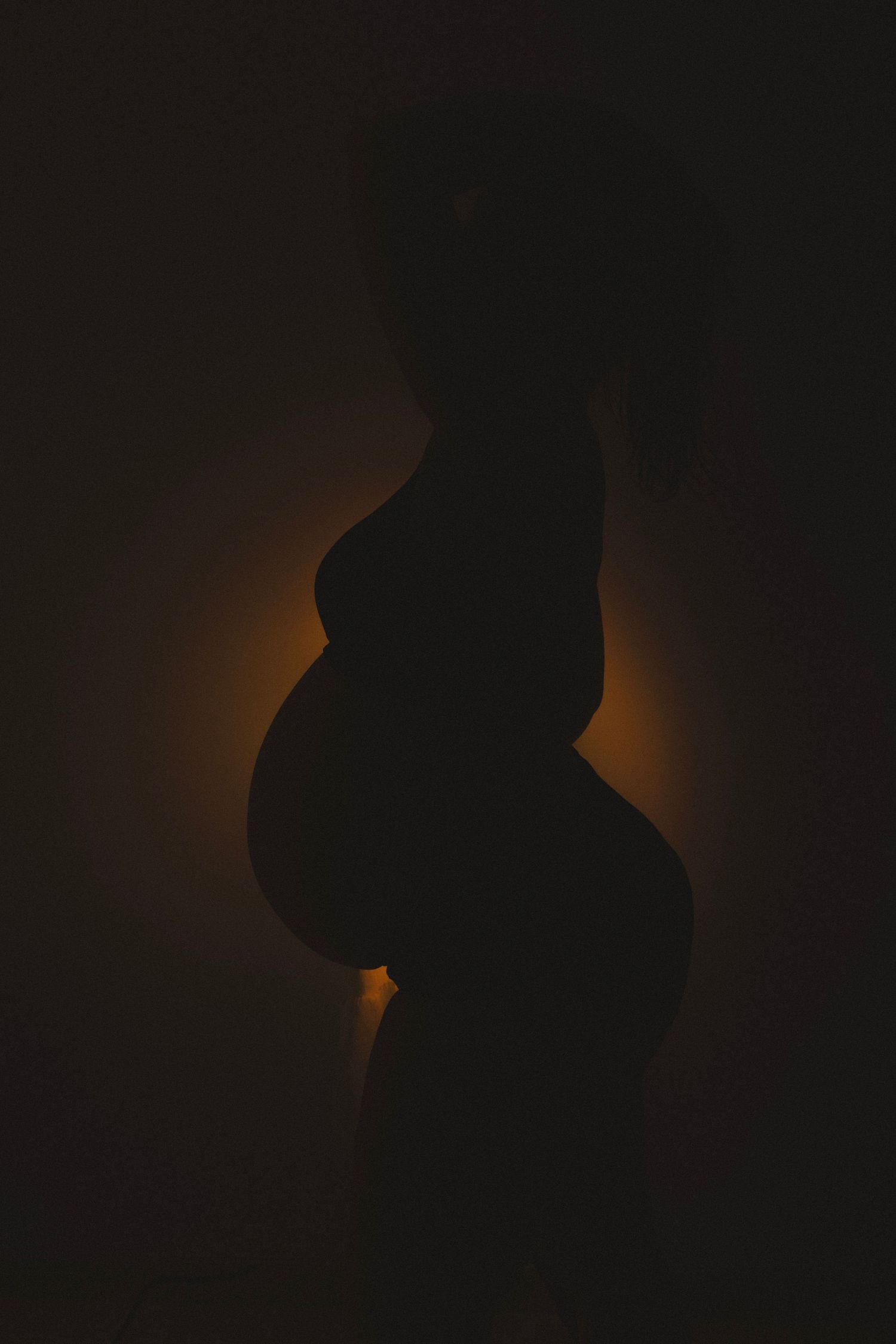 Silhouette artistique de femme enceinte en contre-jour, photo maternité élégante et intime en studio en Provence.