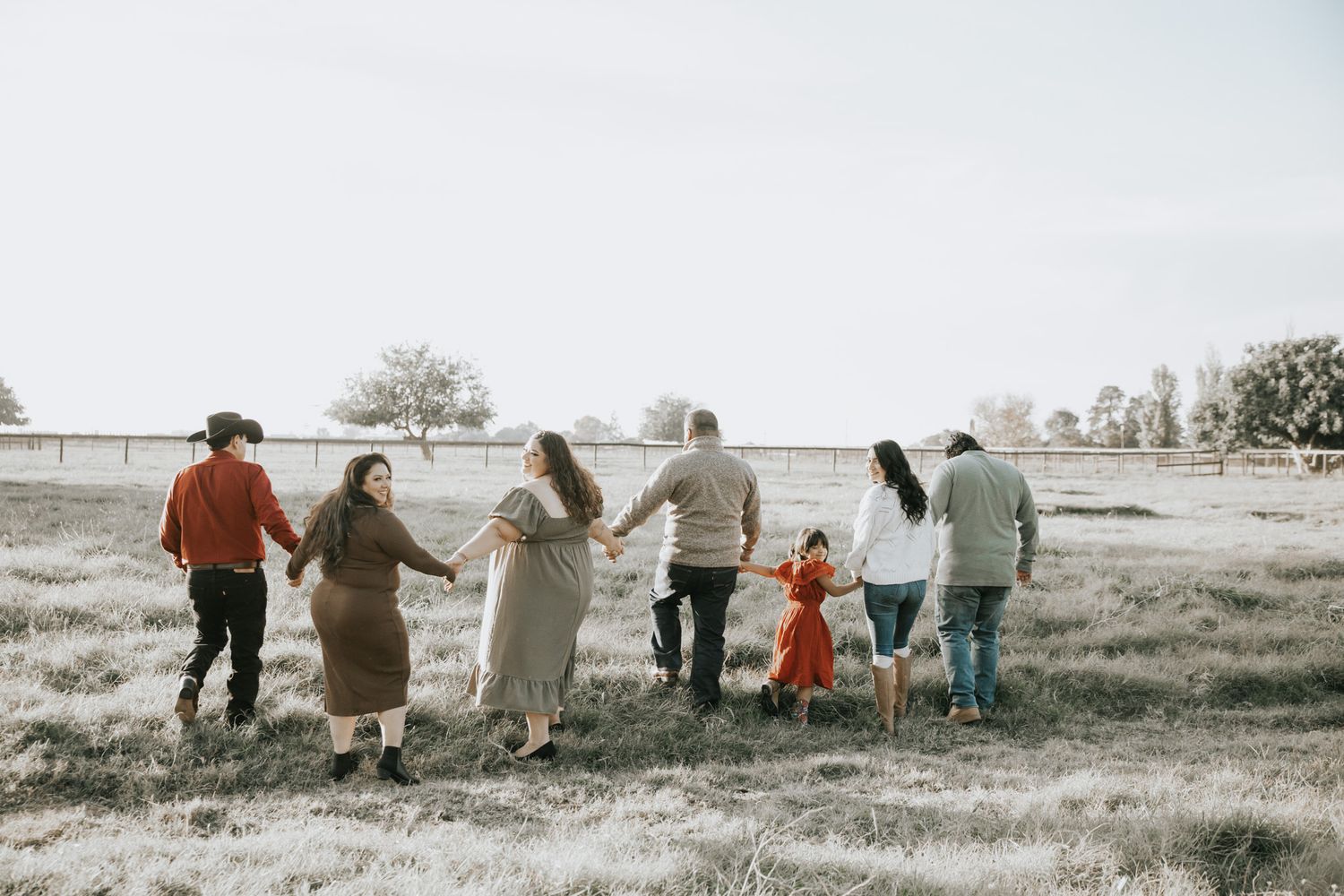 A series of candid black and white photos showing a group of people walking together through a grassy field.