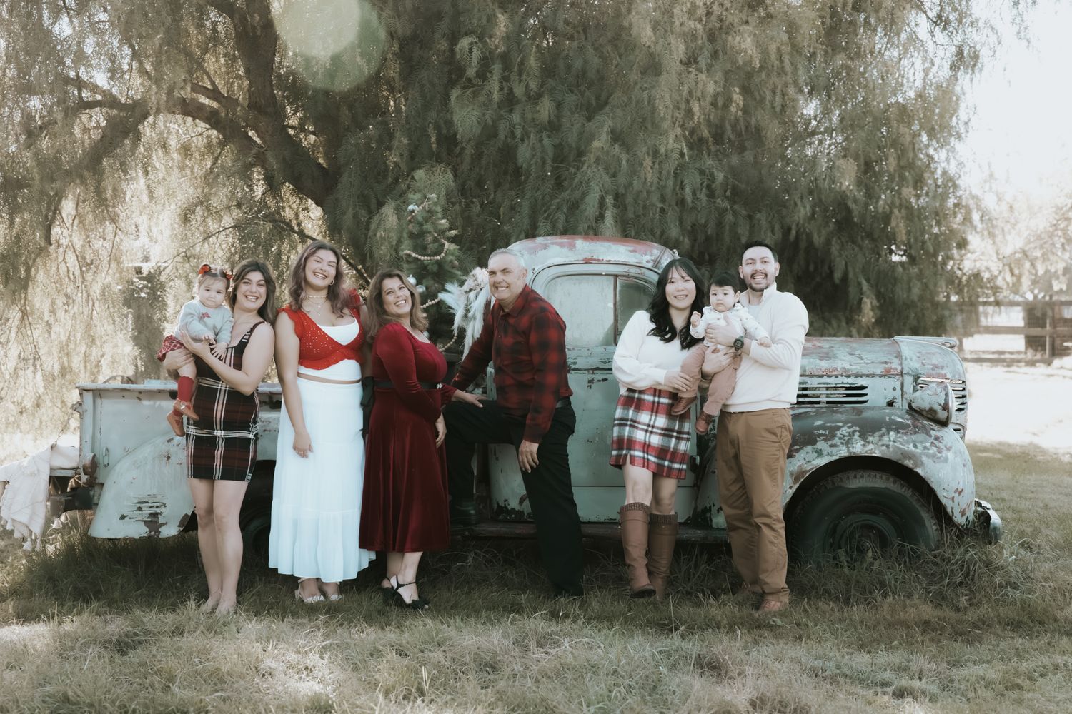 Family photo session outdoors with willow trees creating a dreamy natural backdrop.