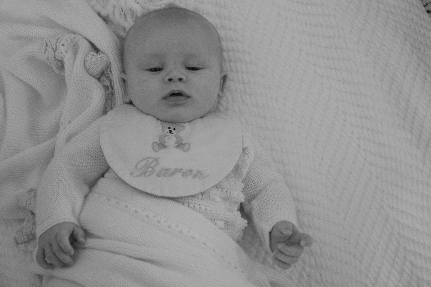 Black and white photo collage showing a sleeping baby in different poses on soft white bedding.