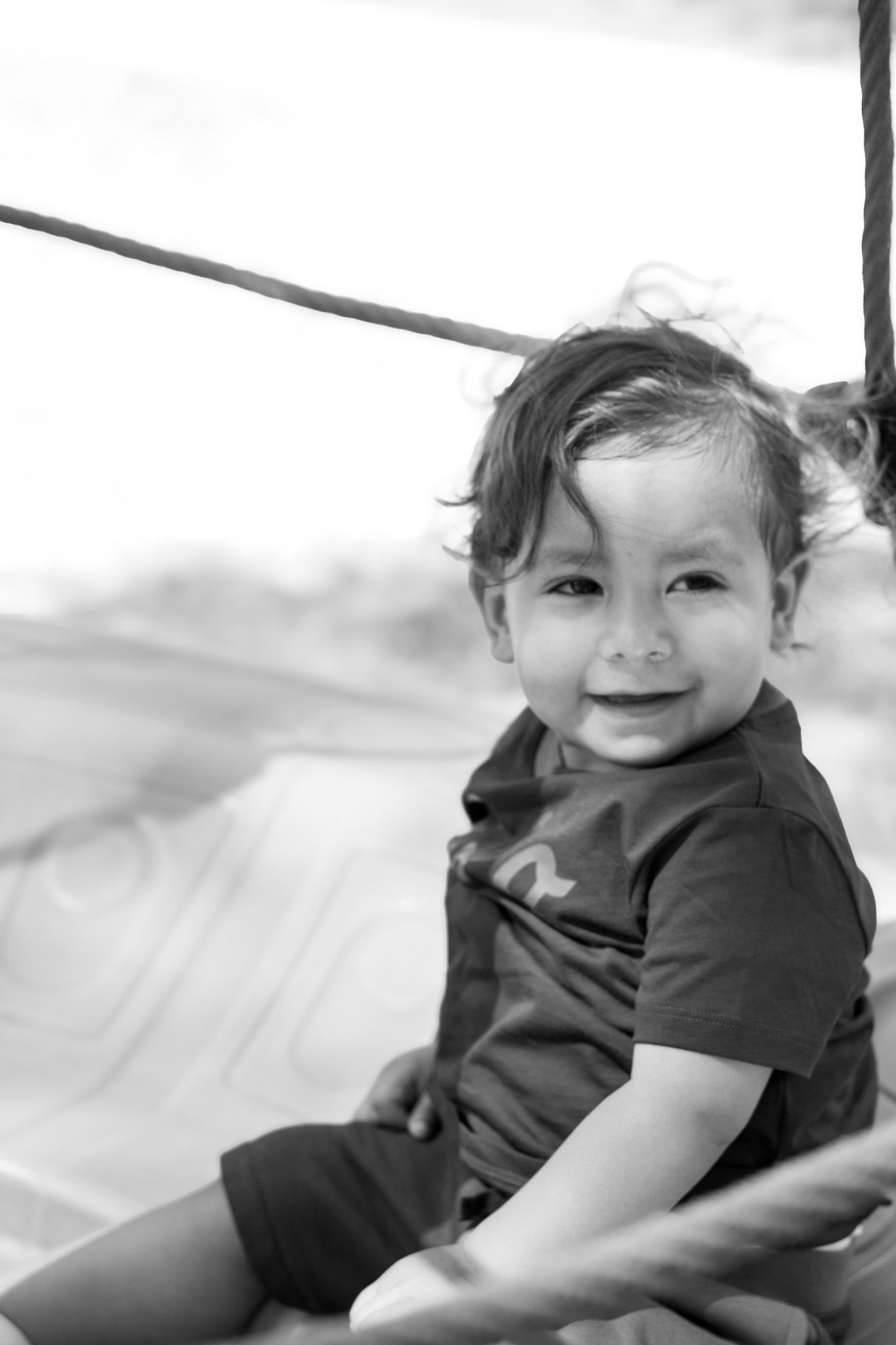 A black and white photo series shows a small child in dark clothing rolling and playing on a light surface.