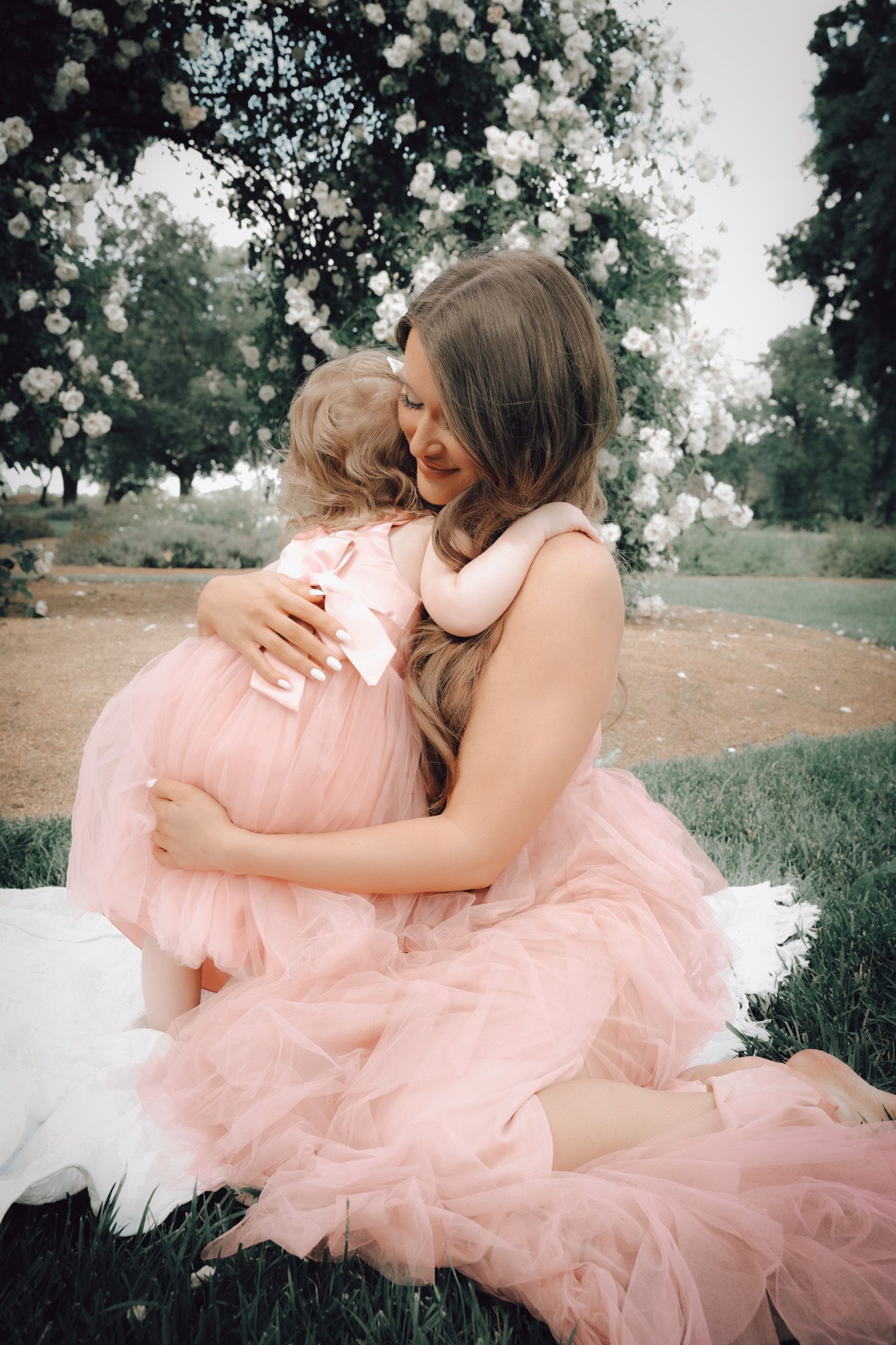 Mother and daughter embracing in the rose garden at Jessie’s Grove Winery, surrounded by blooming flowers from the Oak Grove Flower Company