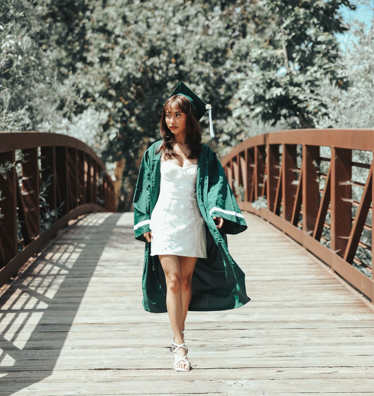 Woman walking on a wooden bridge pathway in white dress and green jacket creating a sequence of movement shots.