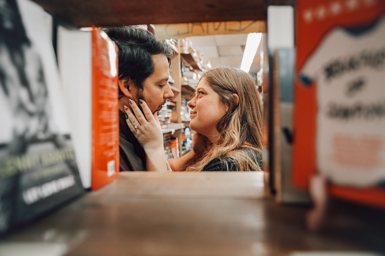Two people share an intimate playful moment while laughing together, framed by a narrow space with red walls.