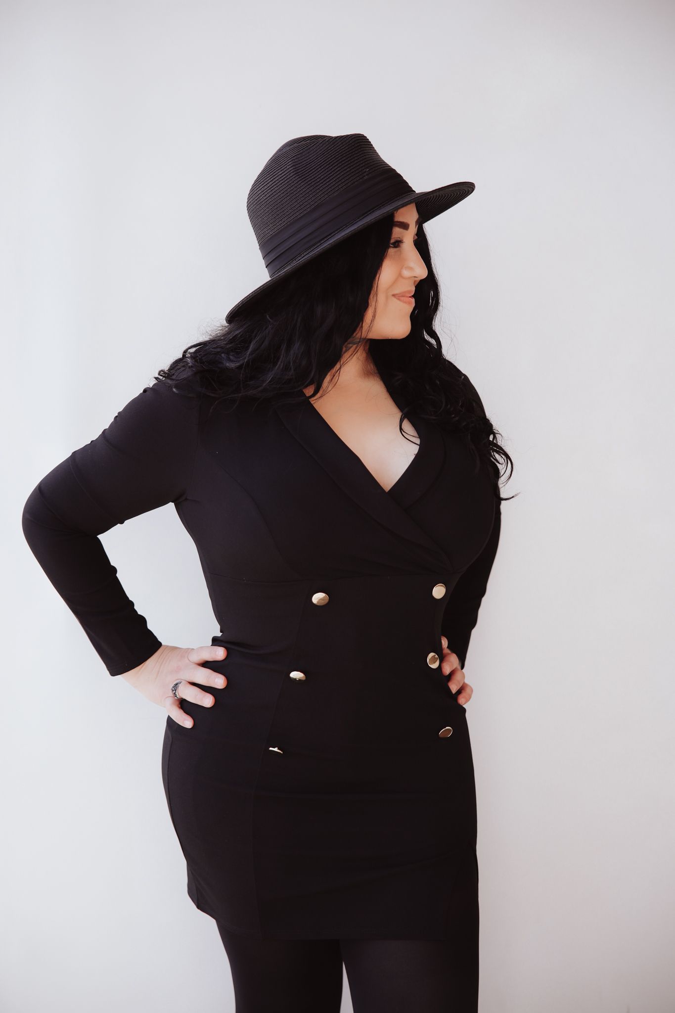 A person wearing a black outfit and wide-brimmed hat poses confidently against a white background in four similar shots.