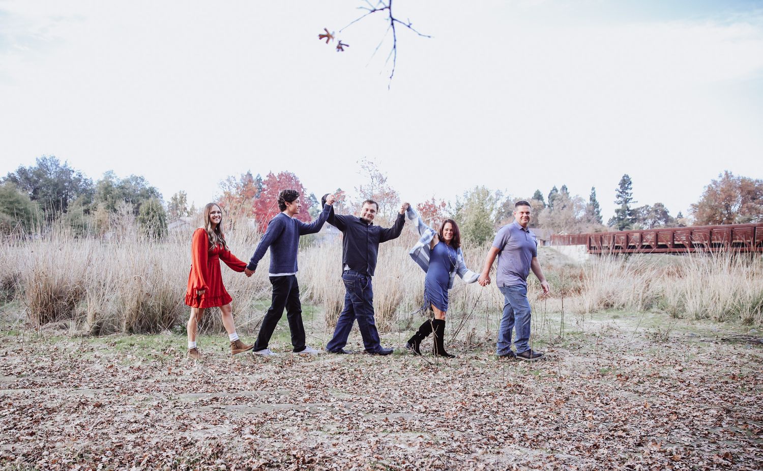 A group in coordinated outfits walks together through a rustic outdoor setting during a photo session.