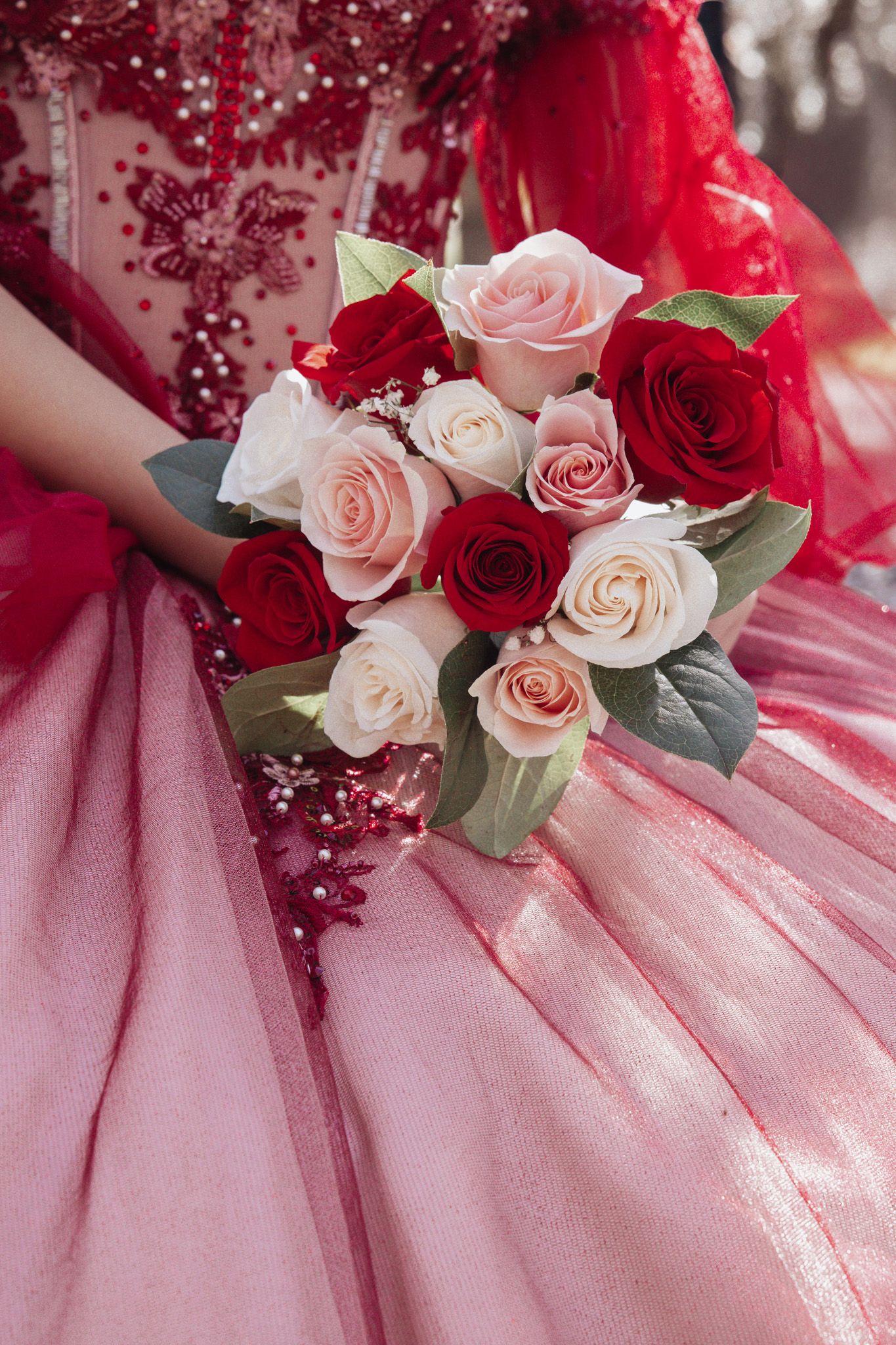 Pink and red roses elegantly arranged on delicate pink tulle fabric create a romantic wedding detail.