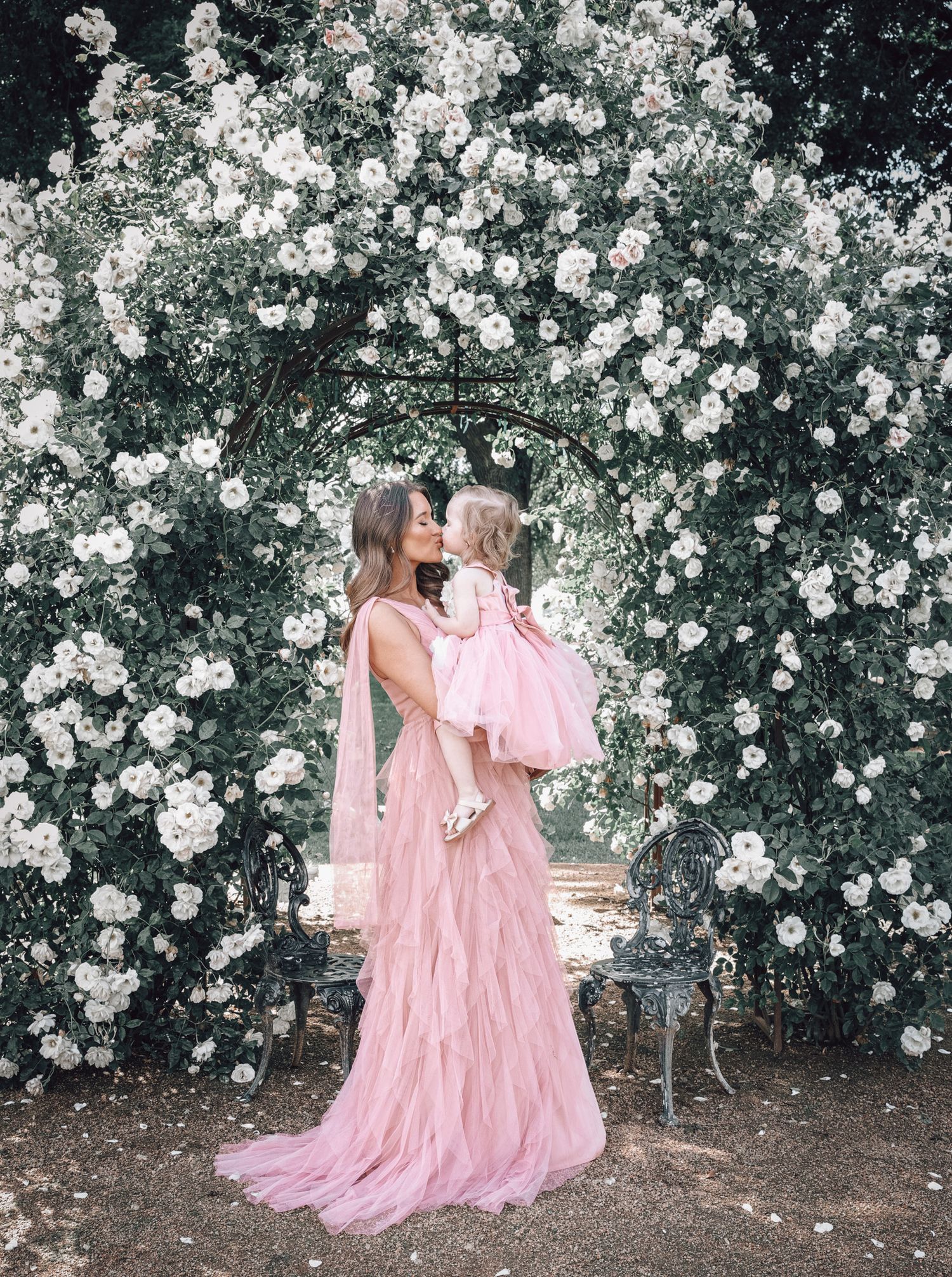 A tender mother‑and‑daughter hug captured in the rose garden at Jessie’s Grove Winery, featuring vibrant florals