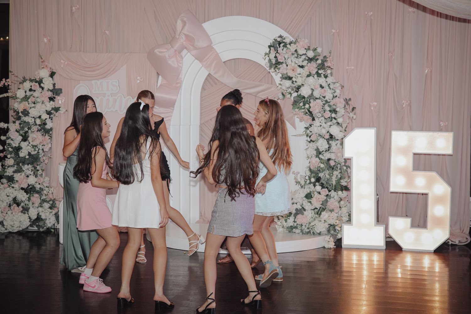 Candid quinceañera photo of the birthday girl dancing with her friends, lively dance floor, joyful expressions, and vibrant party atmosphere