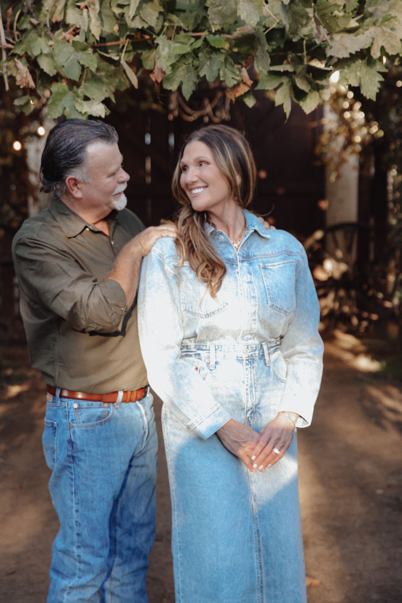 A couple in casual denim and light blue attire share an intimate moment together outdoors.