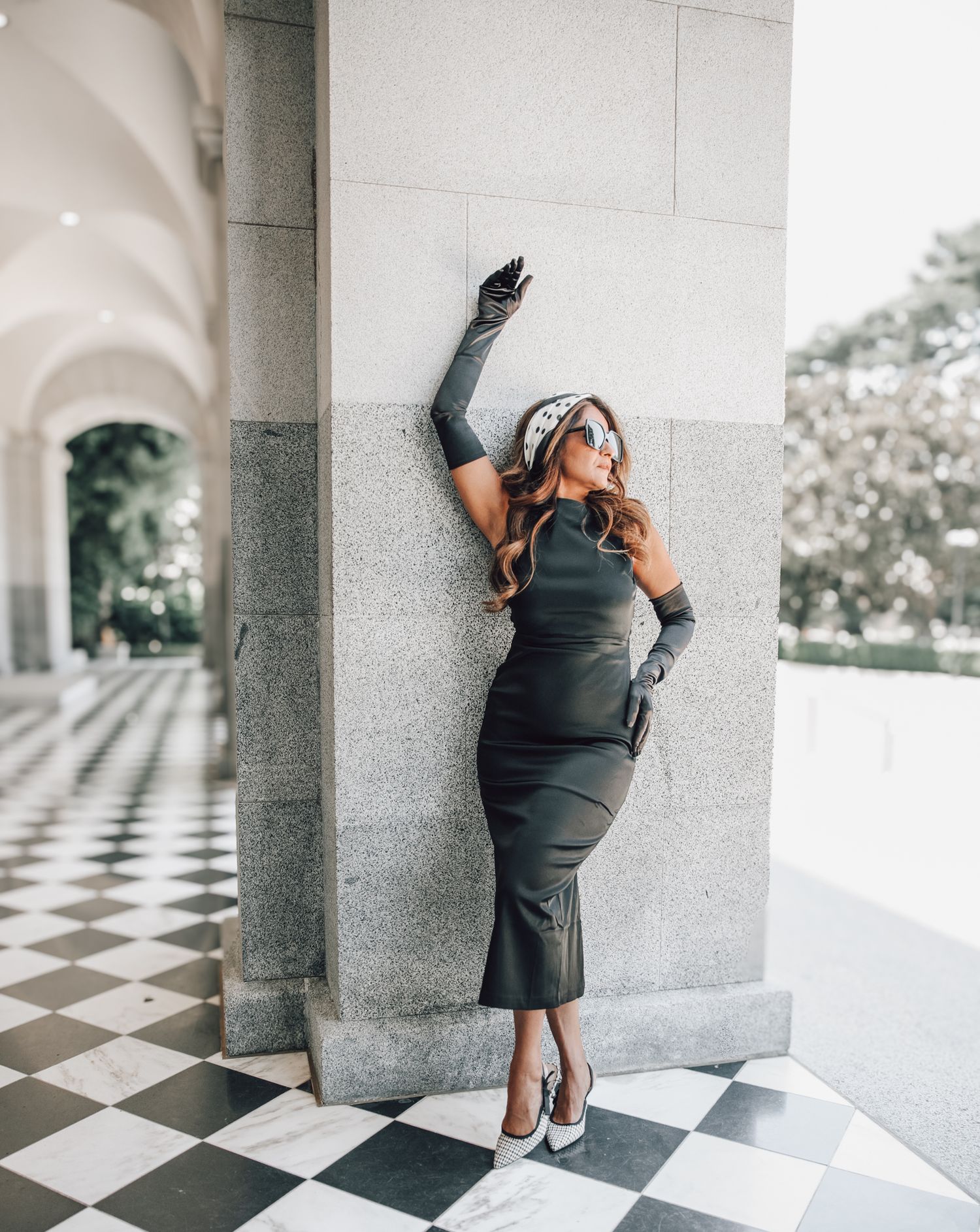 A series of four photos showing someone in professional attire posing against gray stone pillars on a checkerboard floor.