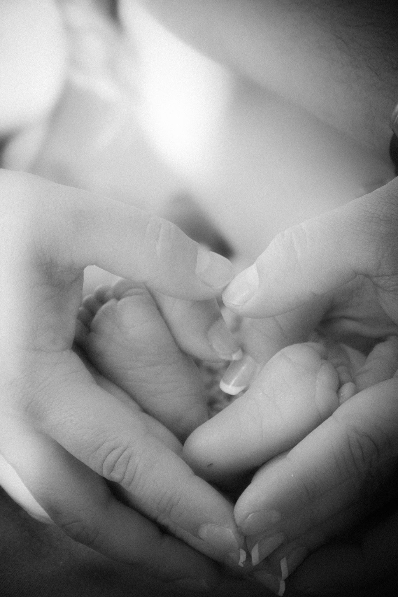 Close-up black and white artistic photograph showing tender newborn fingers in soft focus.