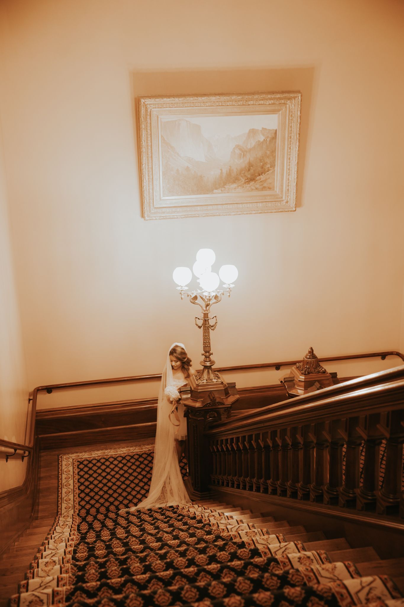 A sepia photograph showing a grand staircase with patterned banisters and white walls in a historic building.